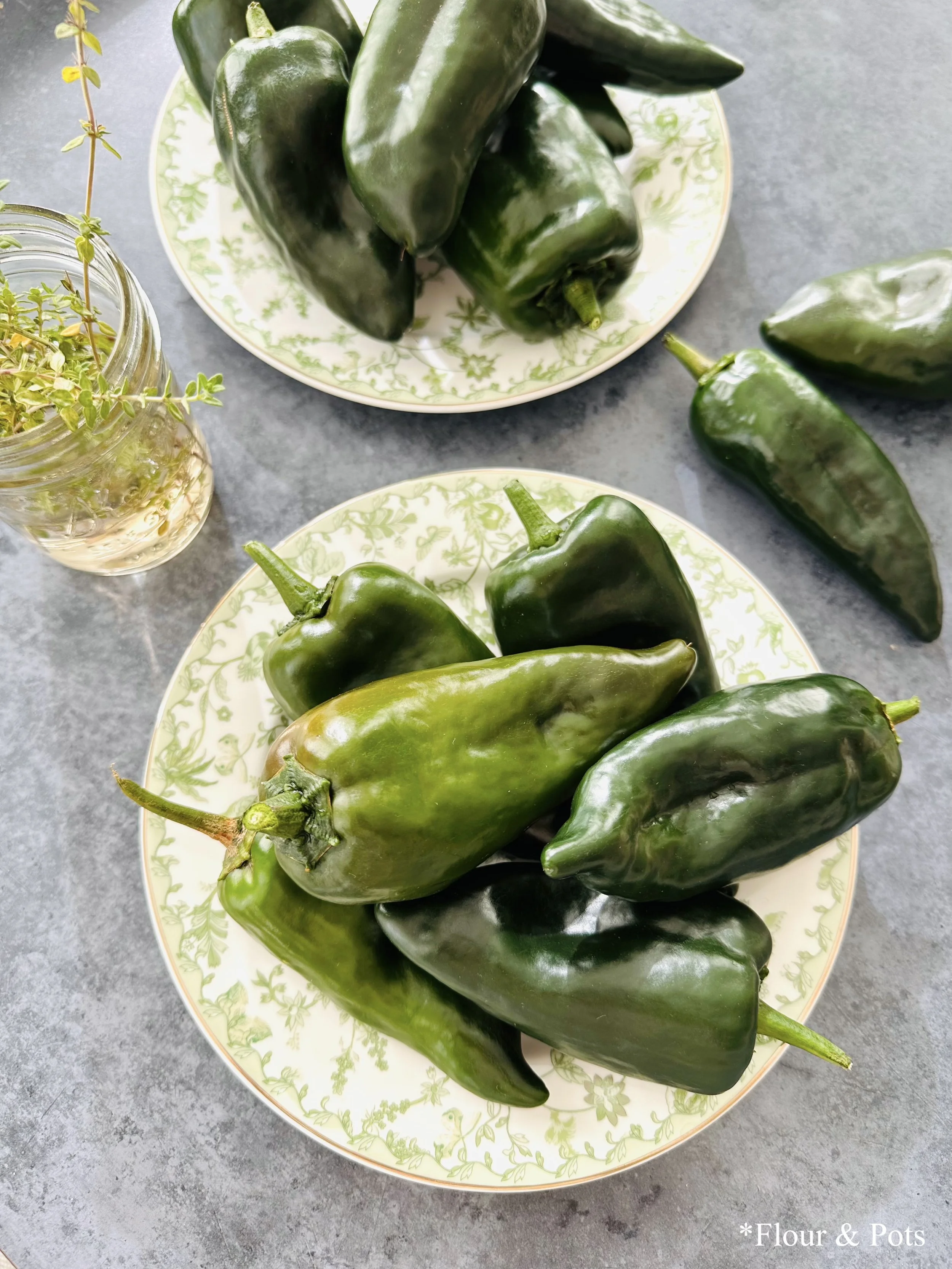 Fresh poblano peppers arranged on a plate, showcasing their deep green color and glossy skin.