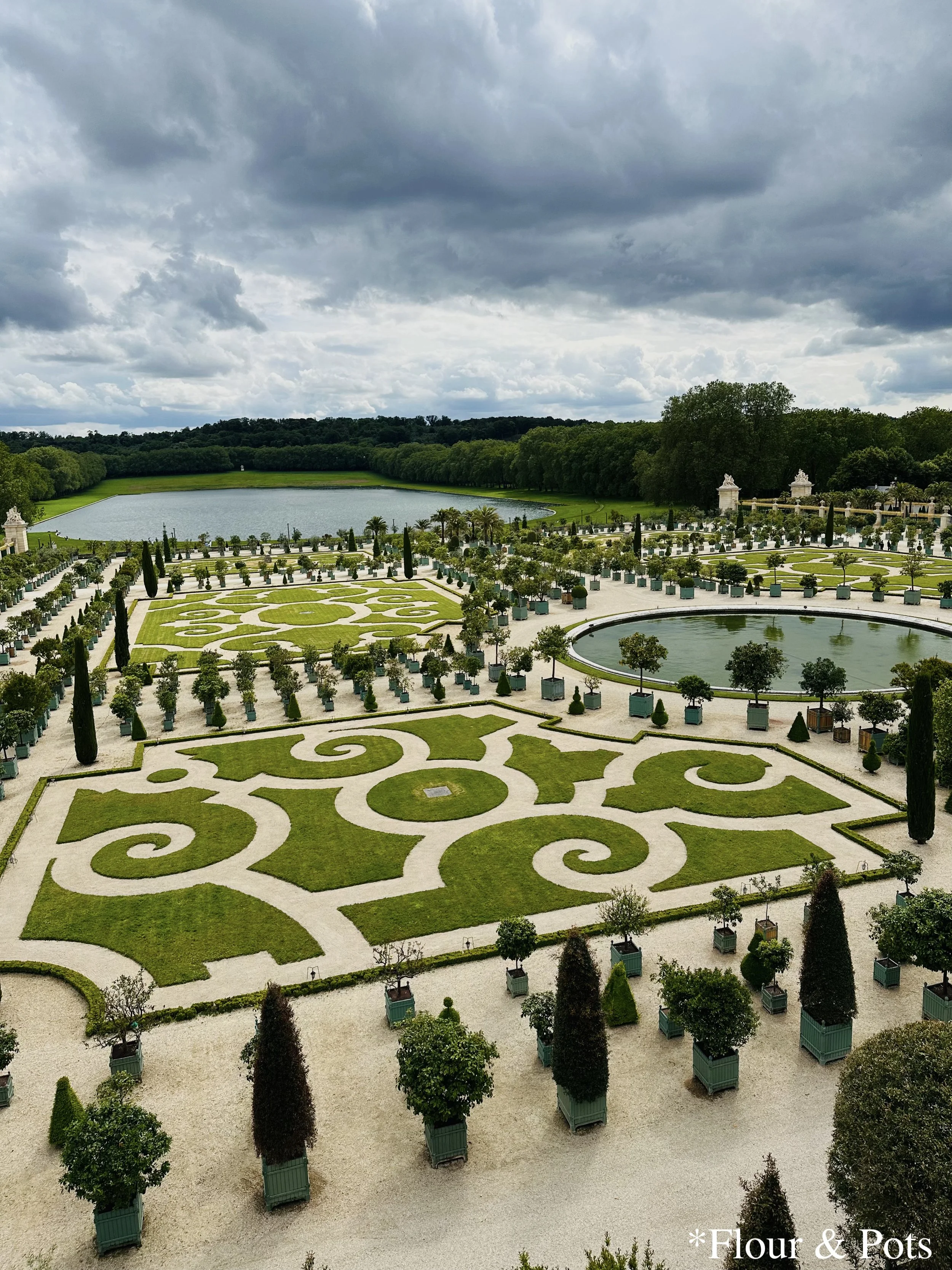 Lush edible garden at Versailles with citrus trees, decorative lawn patterns, and a central pond.