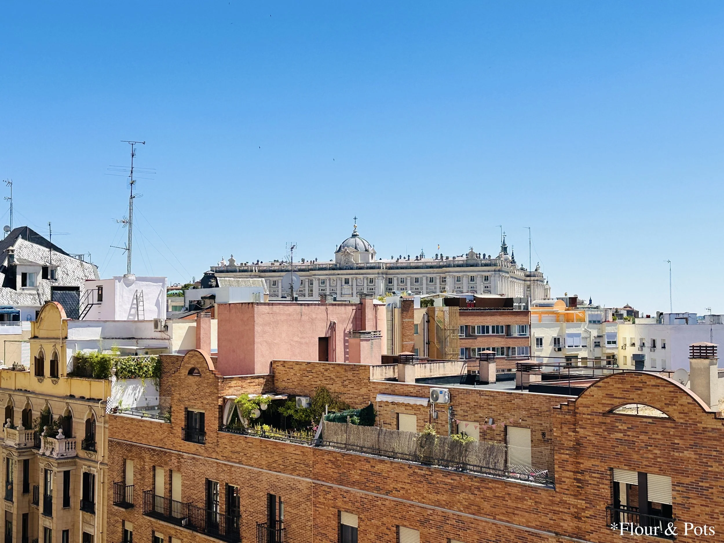 A panoramic rooftop view of Madrid, Spain, showcasing the grand Royal Palace against the backdrop of the city’s skyline.