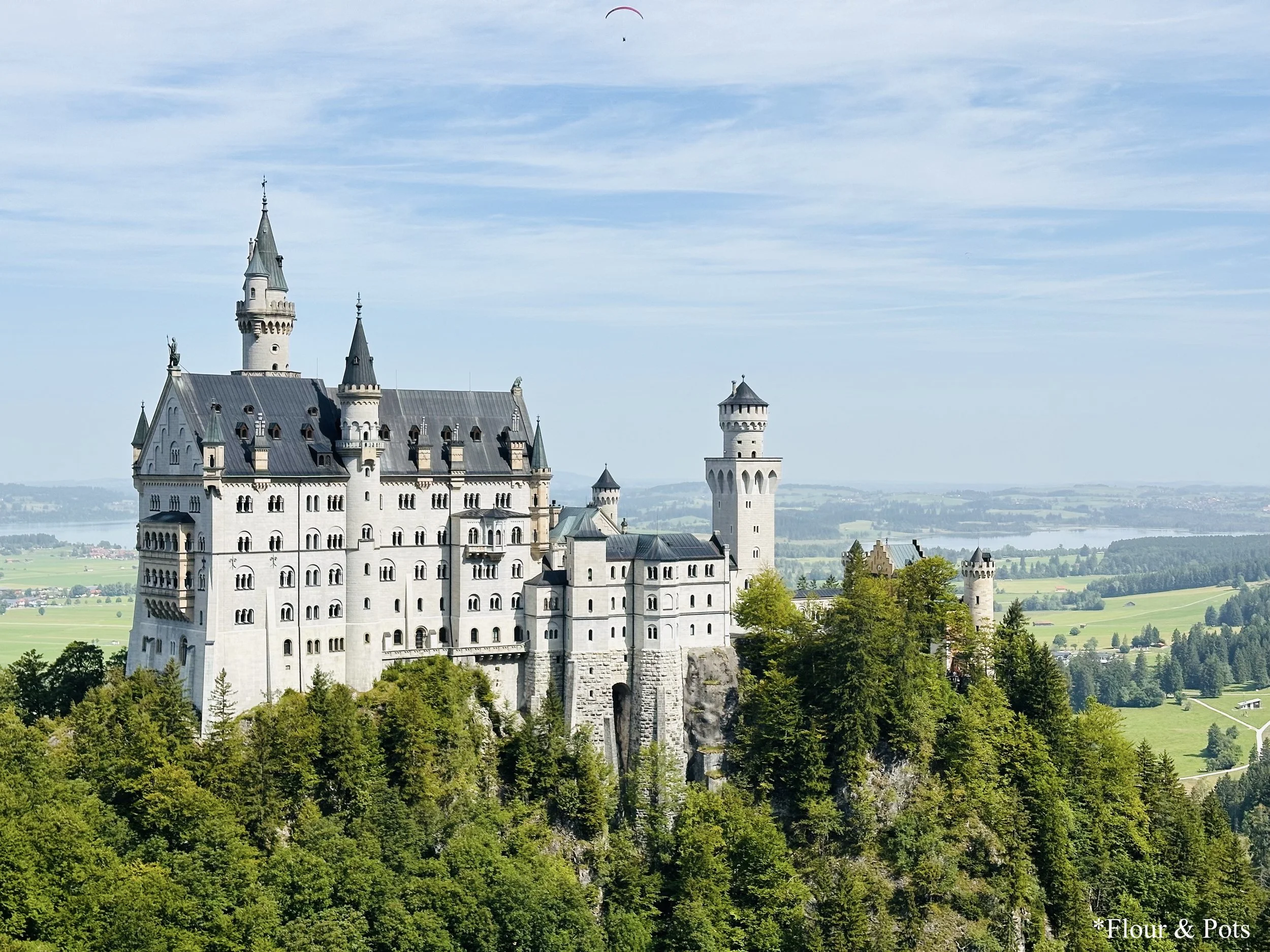 Neuschwanstein Castle viewed from a distance, nestled in the Bavarian Alps with scenic mountain backdrop.