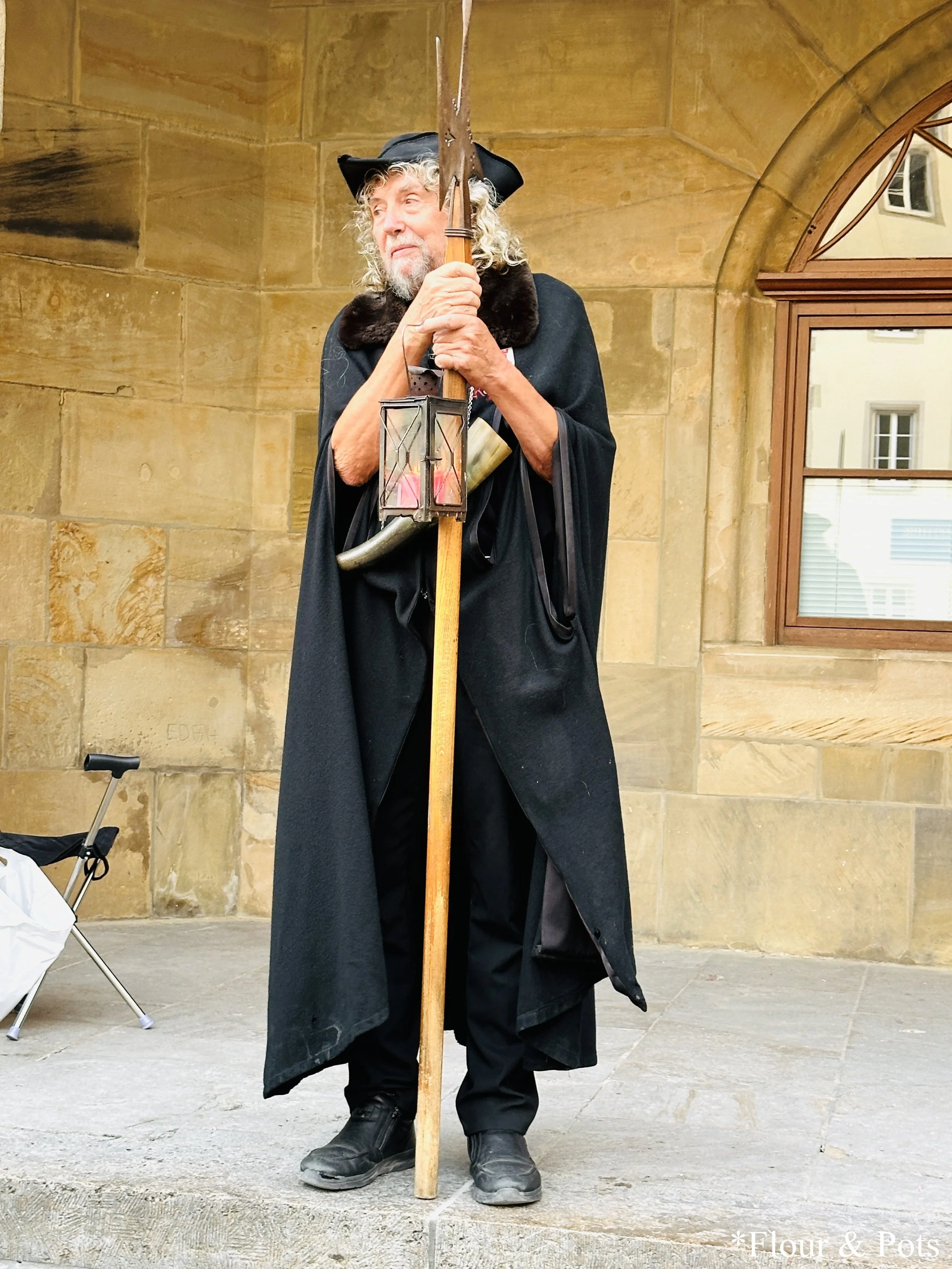 The Night Watchman in Rothenburg, Germany, dressed in traditional medieval attire, leading a tour through the historic streets at night.