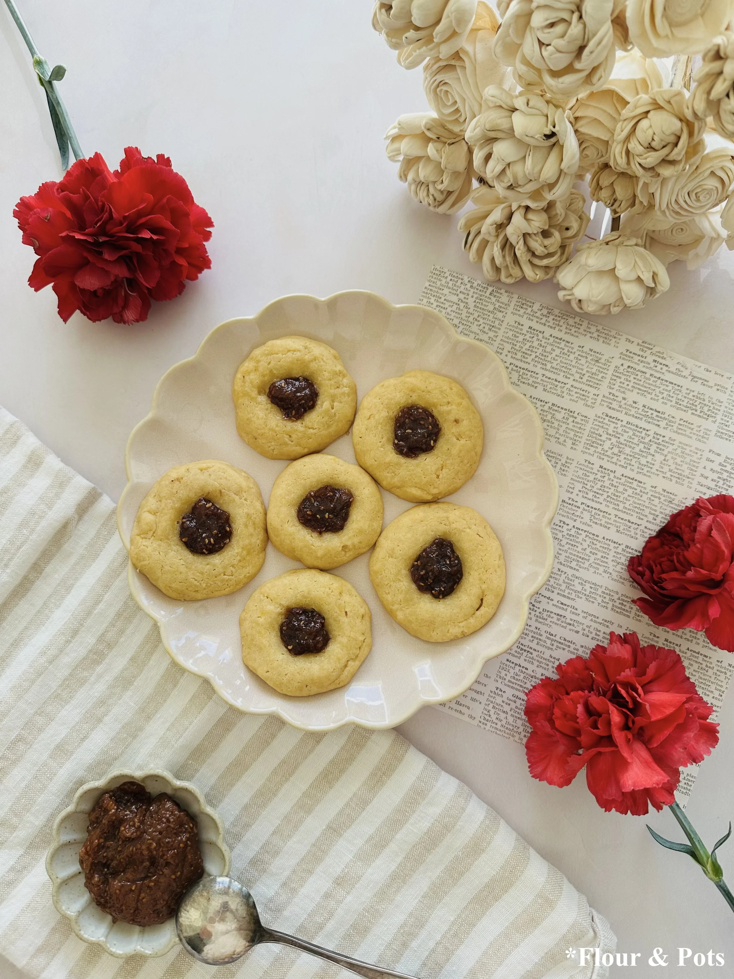 Soft honey thumbprint cookies filled with raspberry chia jam on a plate