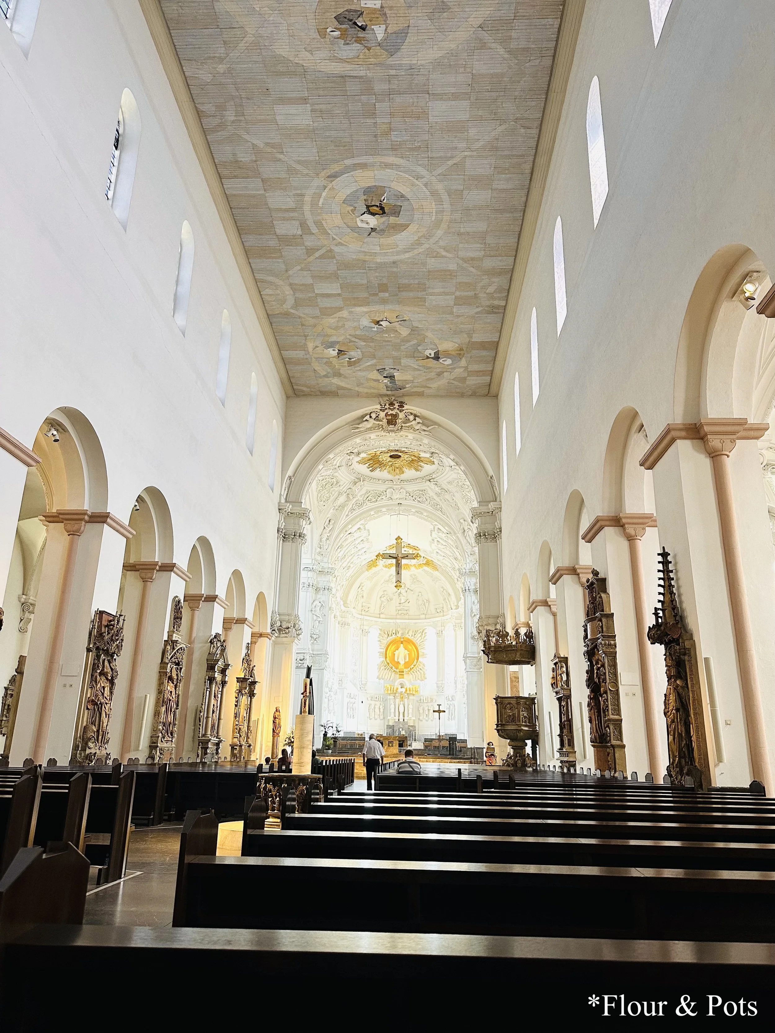 Inside St. Mary’s Chapel in Würzburg, Germany, featuring colorful stained glass windows, stucco walls, and religious artwork.