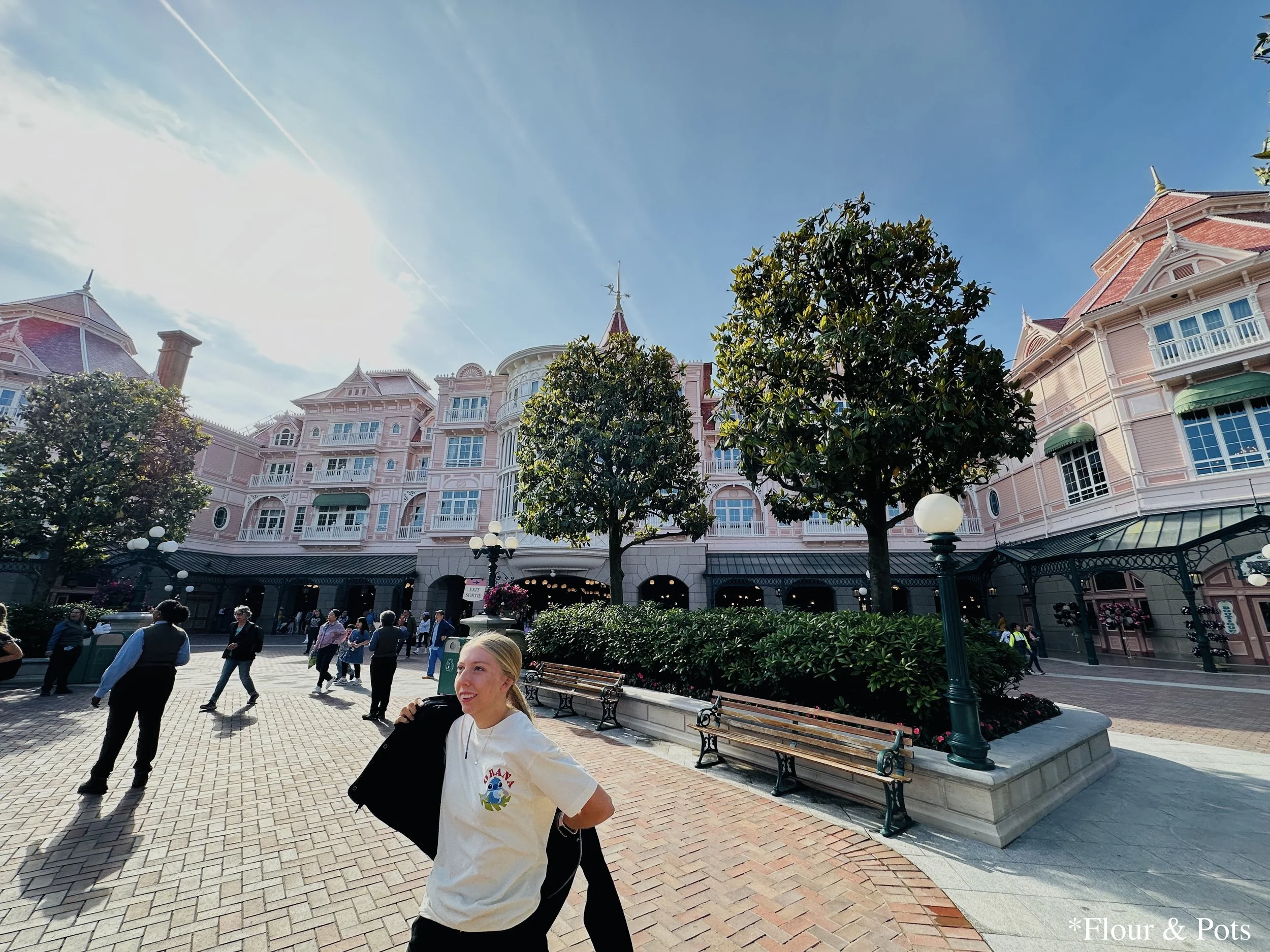 Young girl putting on her jacket to warm up on a cool morning at the entrance of Disneyland Paris, just as the park opens.
