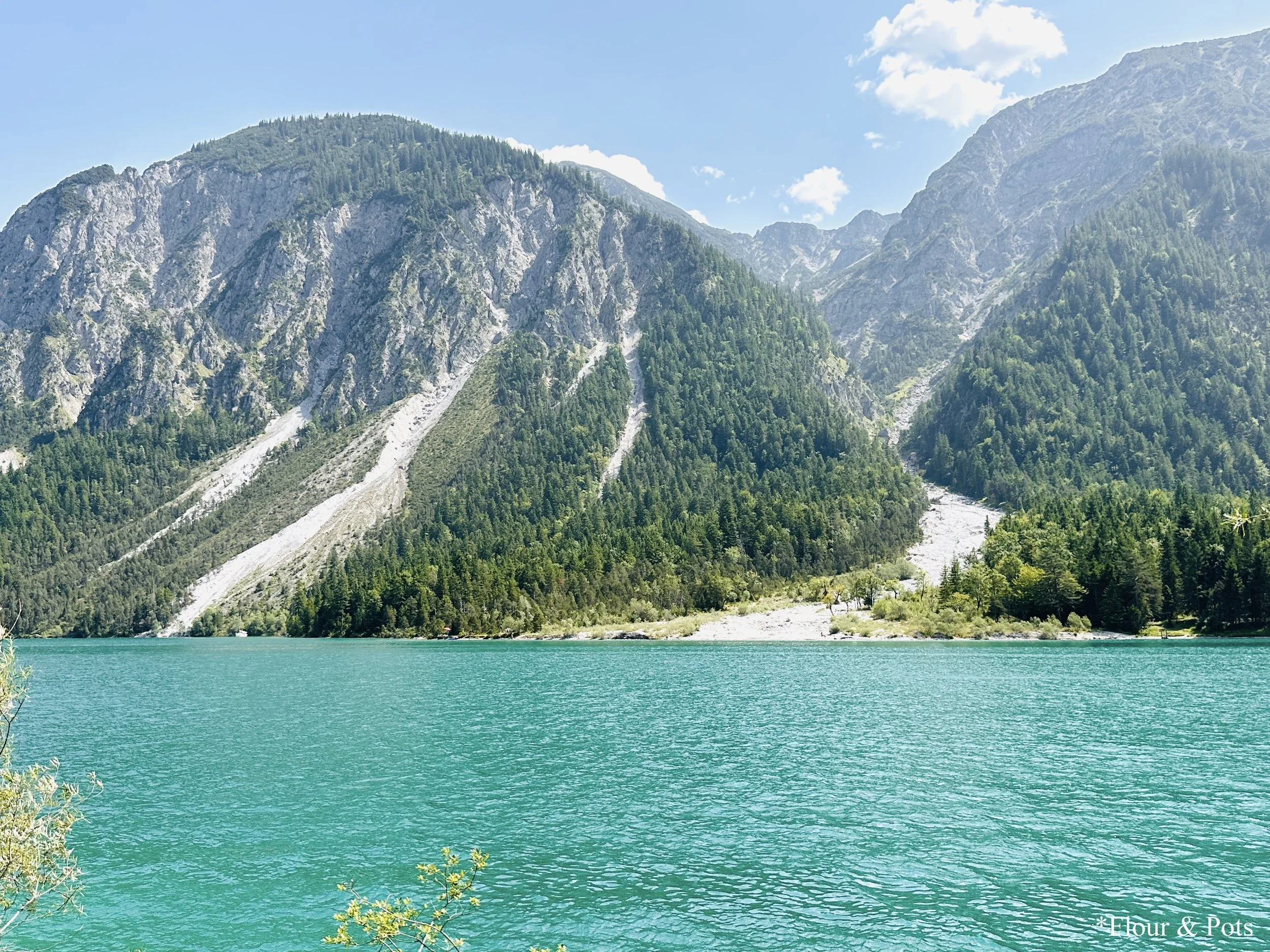 Scenic lake along the route to Munich, Germany, surrounded by lush green landscapes and mountain views.