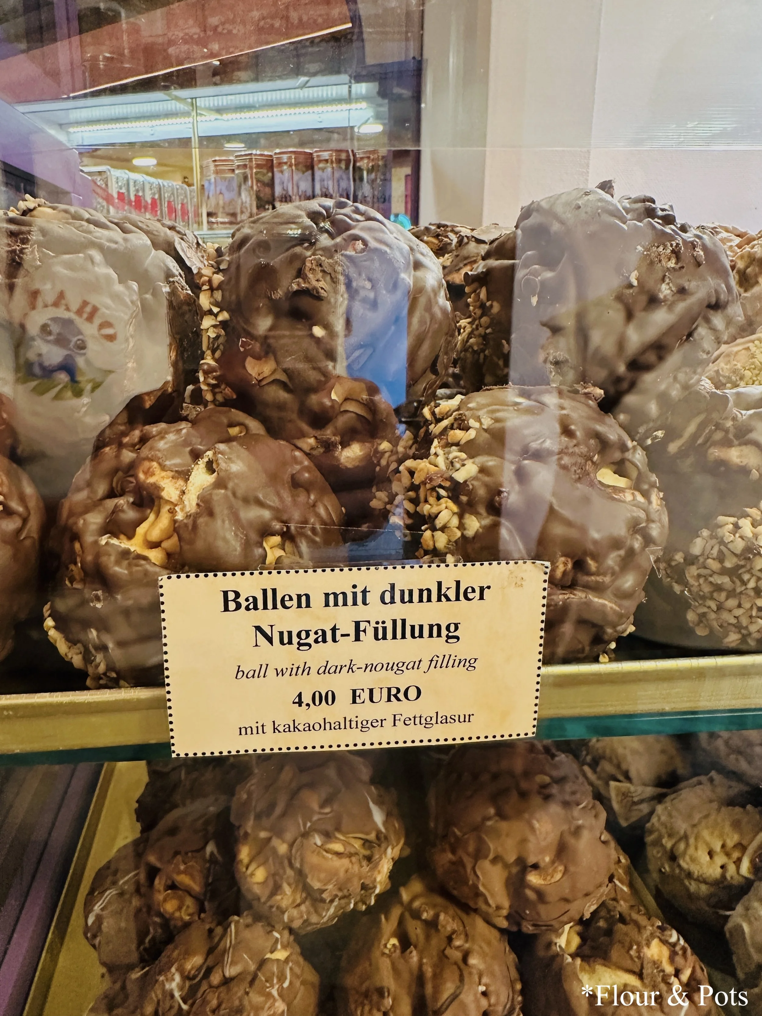Close-up of chocolate snowballs, a local treat from Rothenburg, Germany, displayed in a bakery shop window.