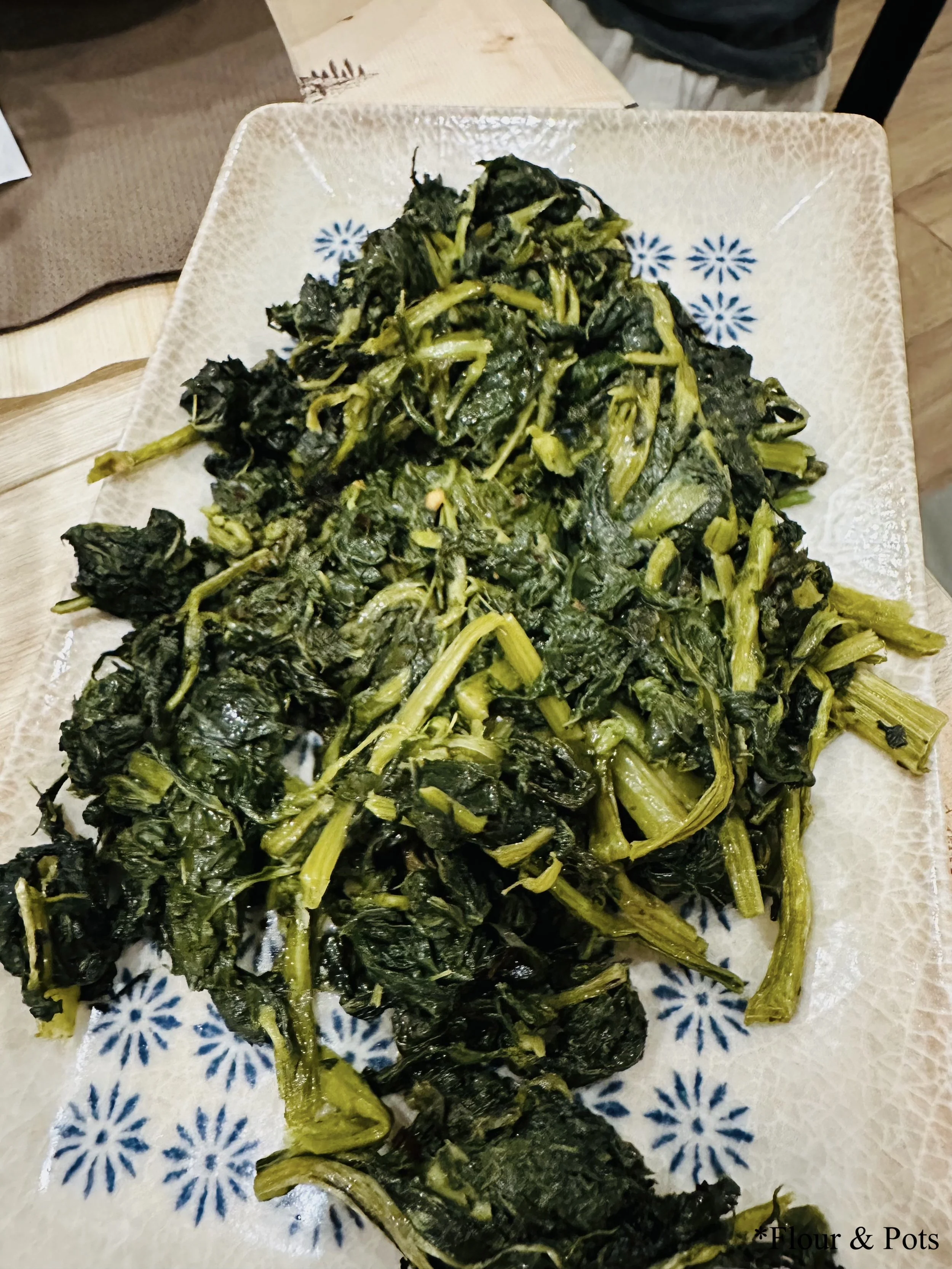 autéed spinach served on a white and blue flower-patterned Roman plate at La Panetteria in Rome, Italy.