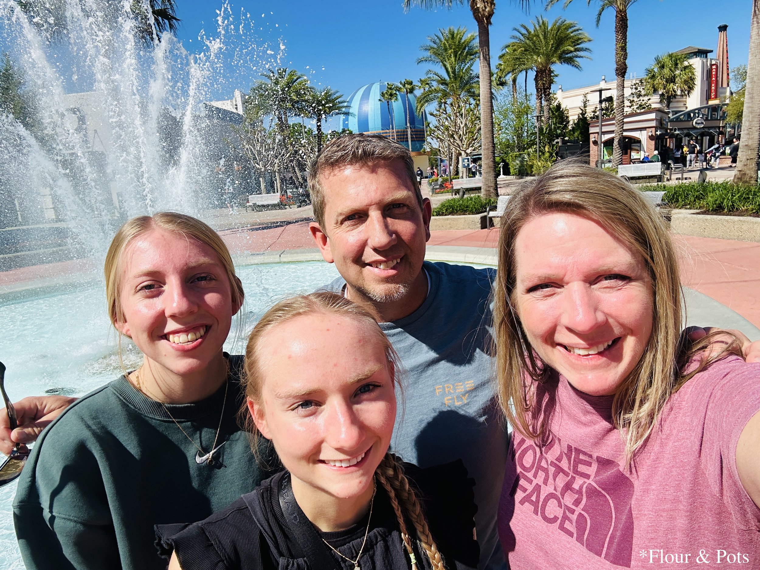Family selfie in front of the main water fountain at Disney Springs in Orlando, Florida.