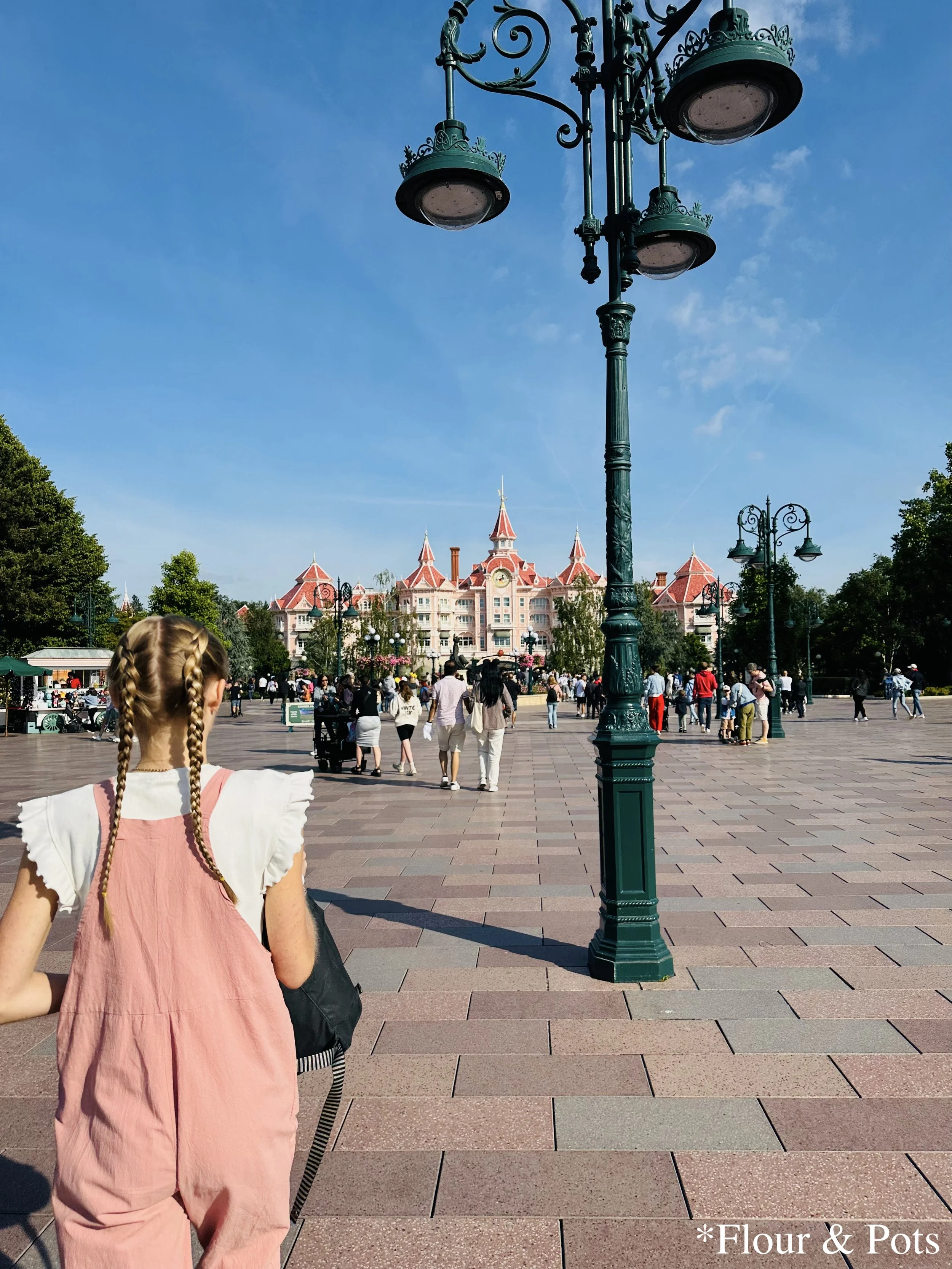 Guest walking toward the central plaza of Disneyland Paris, with the elegant pink Disneyland Hotel in the frontground.