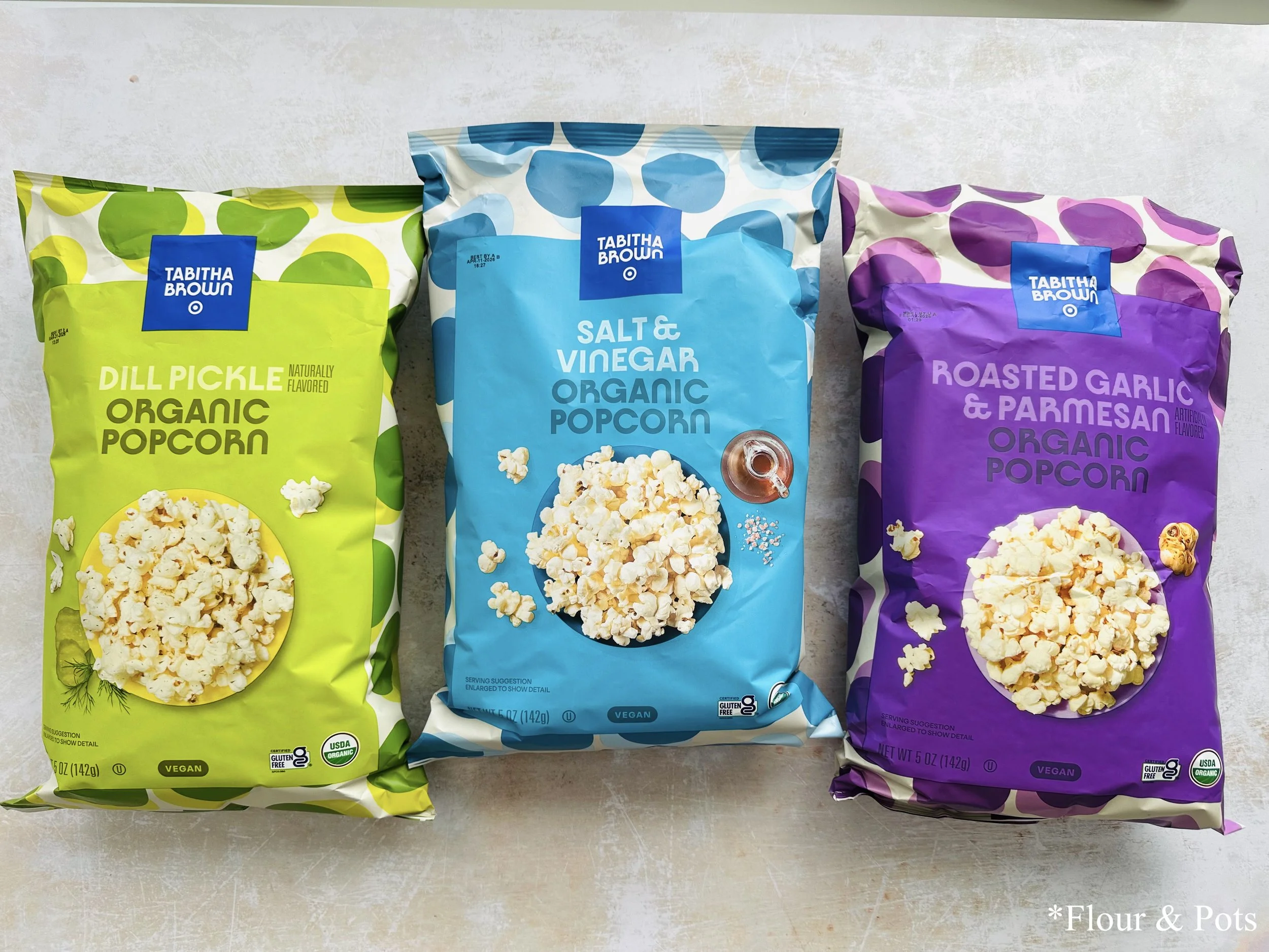 All three flavors of Target’s Tabitha Brown Organic Popcorn—Salt & Vinegar, Dill Pickle, and Roasted Garlic & Parmesan—displayed together.