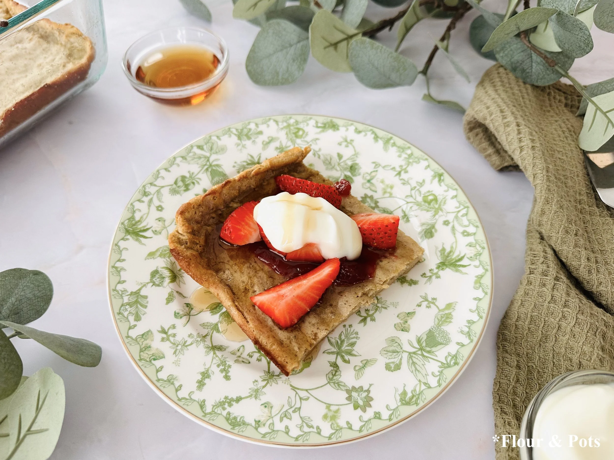 Protein-rich German pancake topped with fresh strawberries and maple syrup