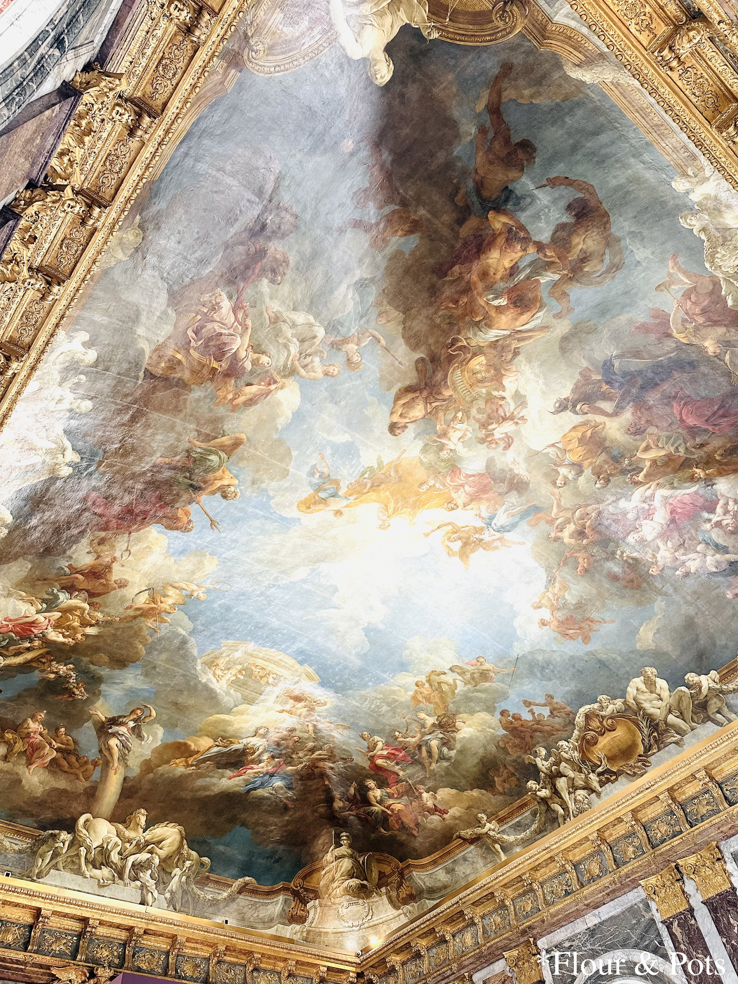 Stunning painted ceiling inside the Palace of Versailles with intricate artwork and ornate designs.