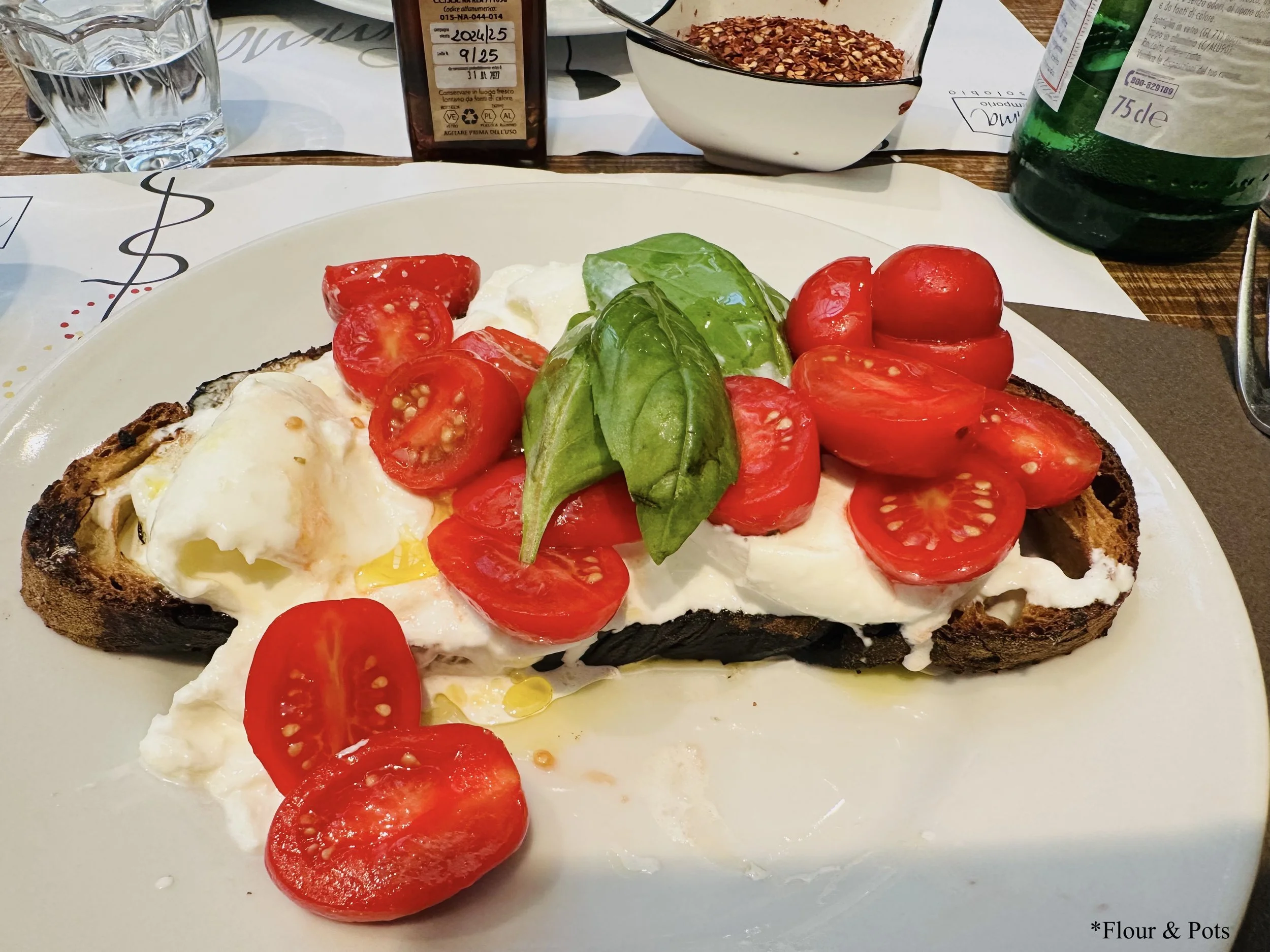 Bruschetta topped with creamy burrata cheese, cherry tomatoes, olive oil, and fresh basil at Emma, a Roman-style restaurant in Rome, Italy.