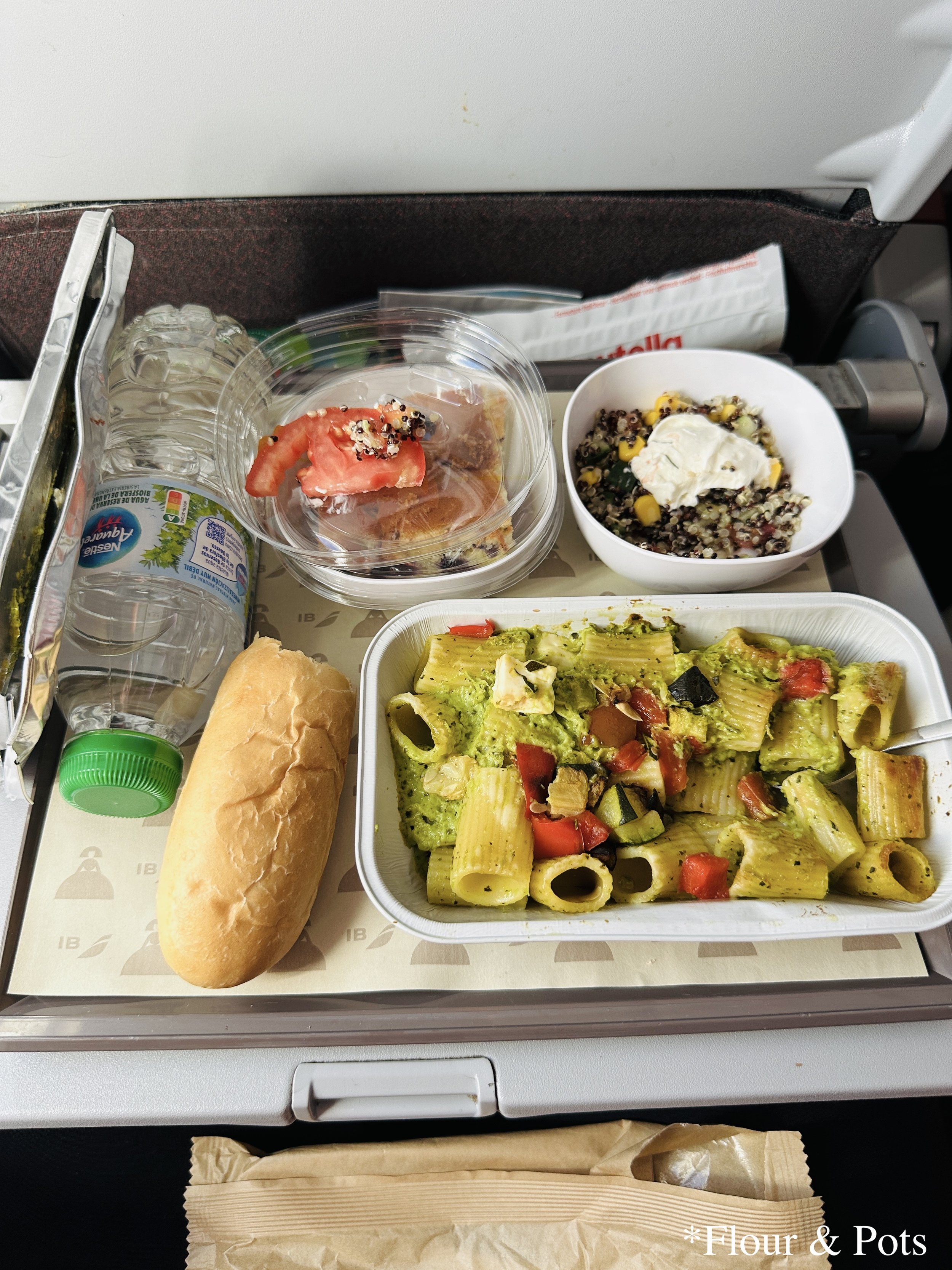 A pasta dinner served on an Iberia flight from Madrid (MAD) to Dallas/Fort Worth (DFW), featuring red pepper, zucchini, and pesto.