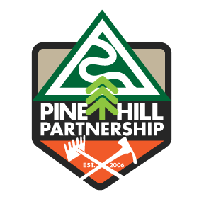 Pine Hill Partnership logo with a green triangle, white pine tree, and upward arrow, with text and icons of a hand and a tool.