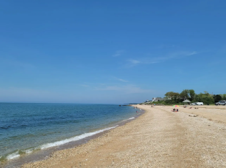 Empty sandy beach with a view of the ocean and a clear blue sky.