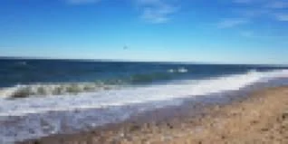 Beach with ocean waves and a clear blue sky.