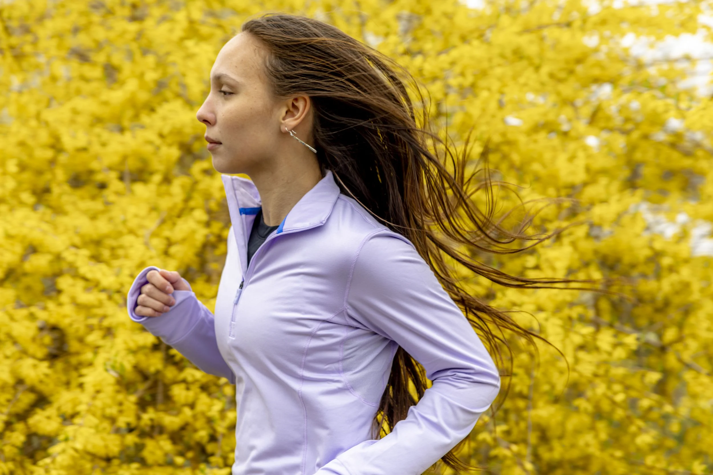 A woman running outdoors with yellow foliage in the background.