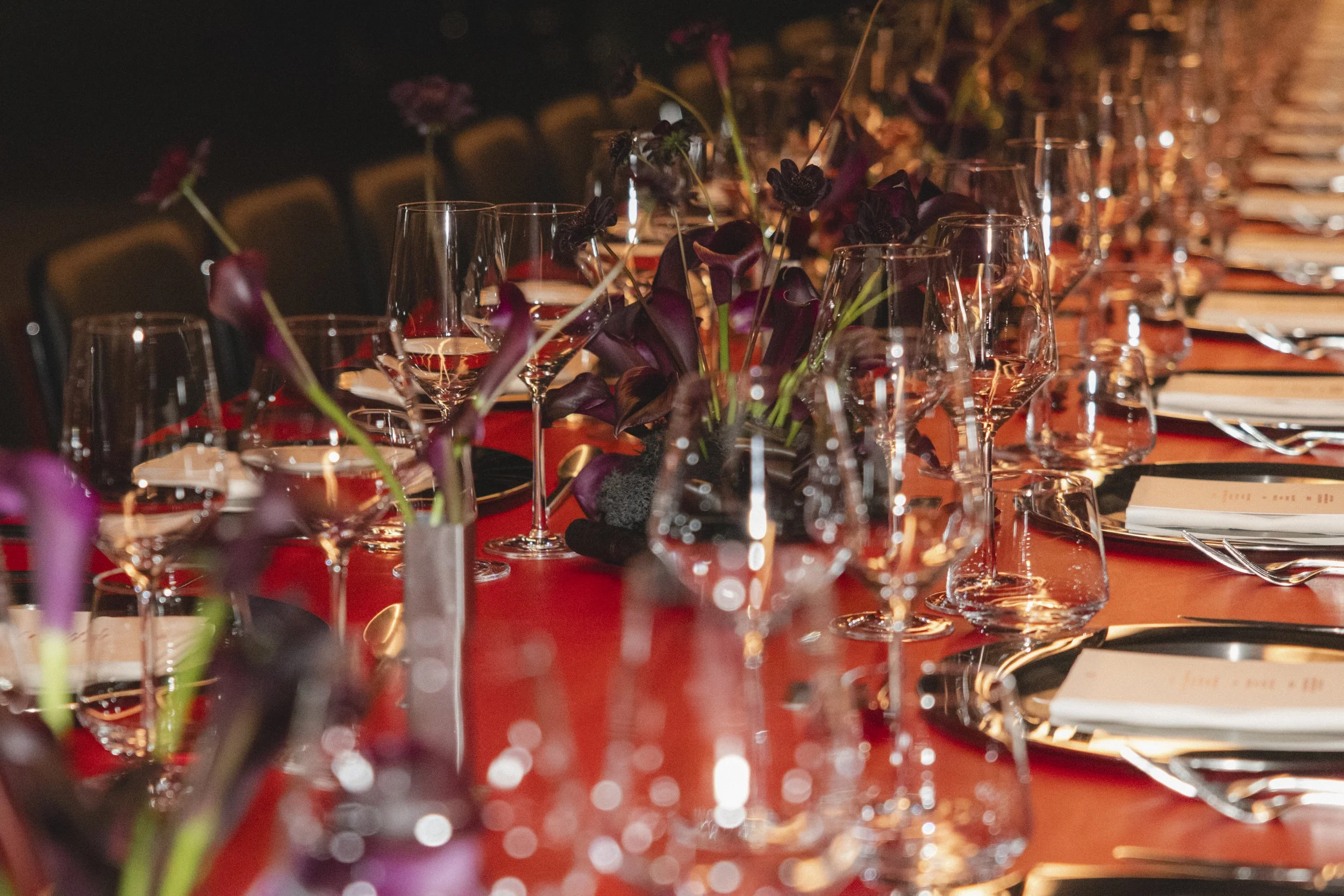 Elegant banquet table with wine glasses, purple flowers, and place settings, set for a formal event or dinner