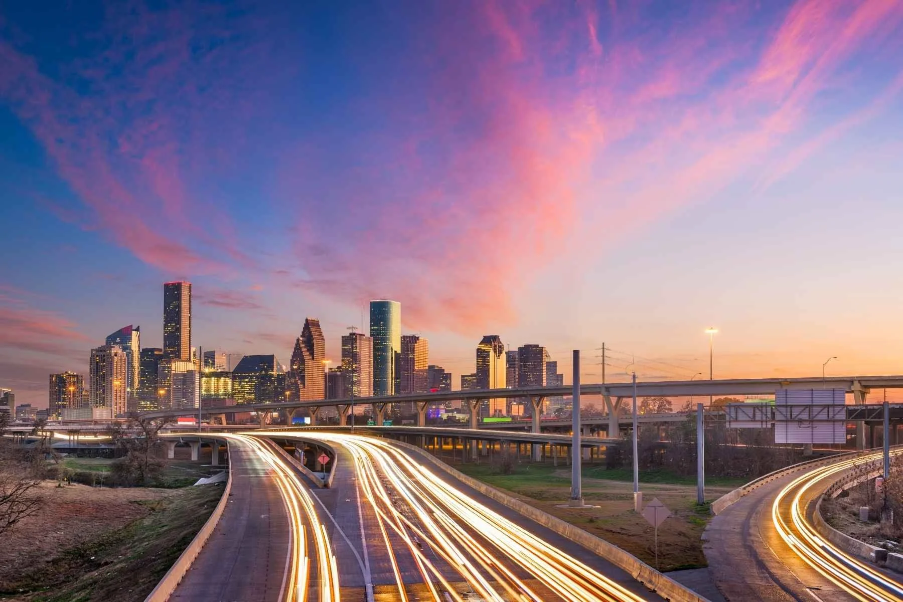 Vibrant sunset over the Houston skyline and highway overpass, perfect for launching travel trailer rentals adventures