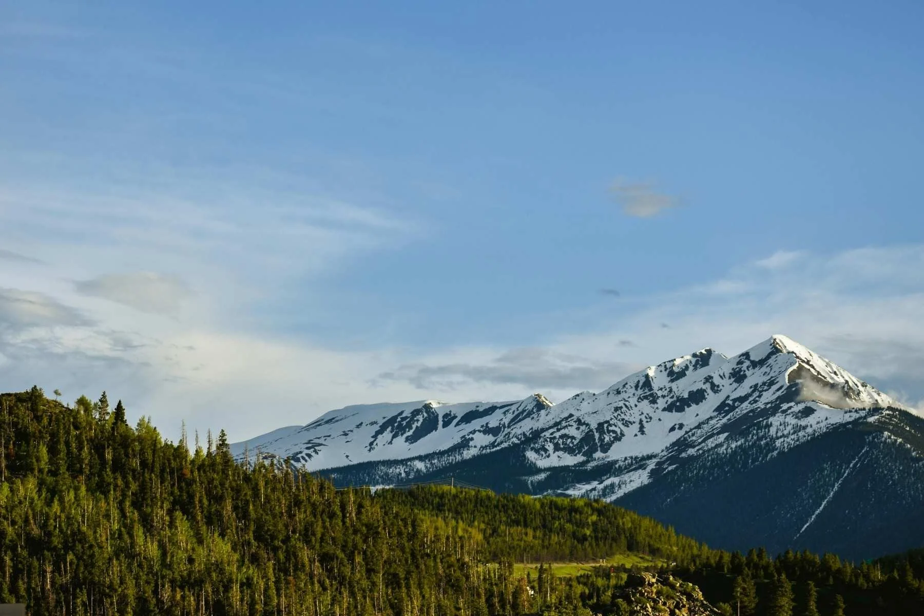 Snow-capped Rocky Mountain peaks above an evergreen forest near Denver, Colorado, a popular travel trailer rental destination