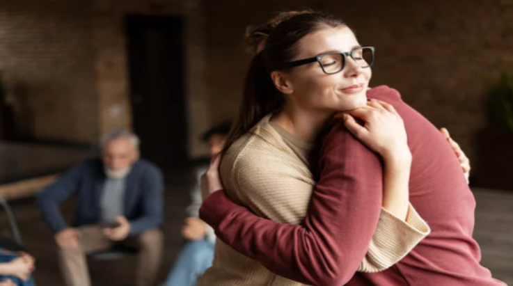A woman offering a comforting hug in a support group, showing how to help someone heal from trauma