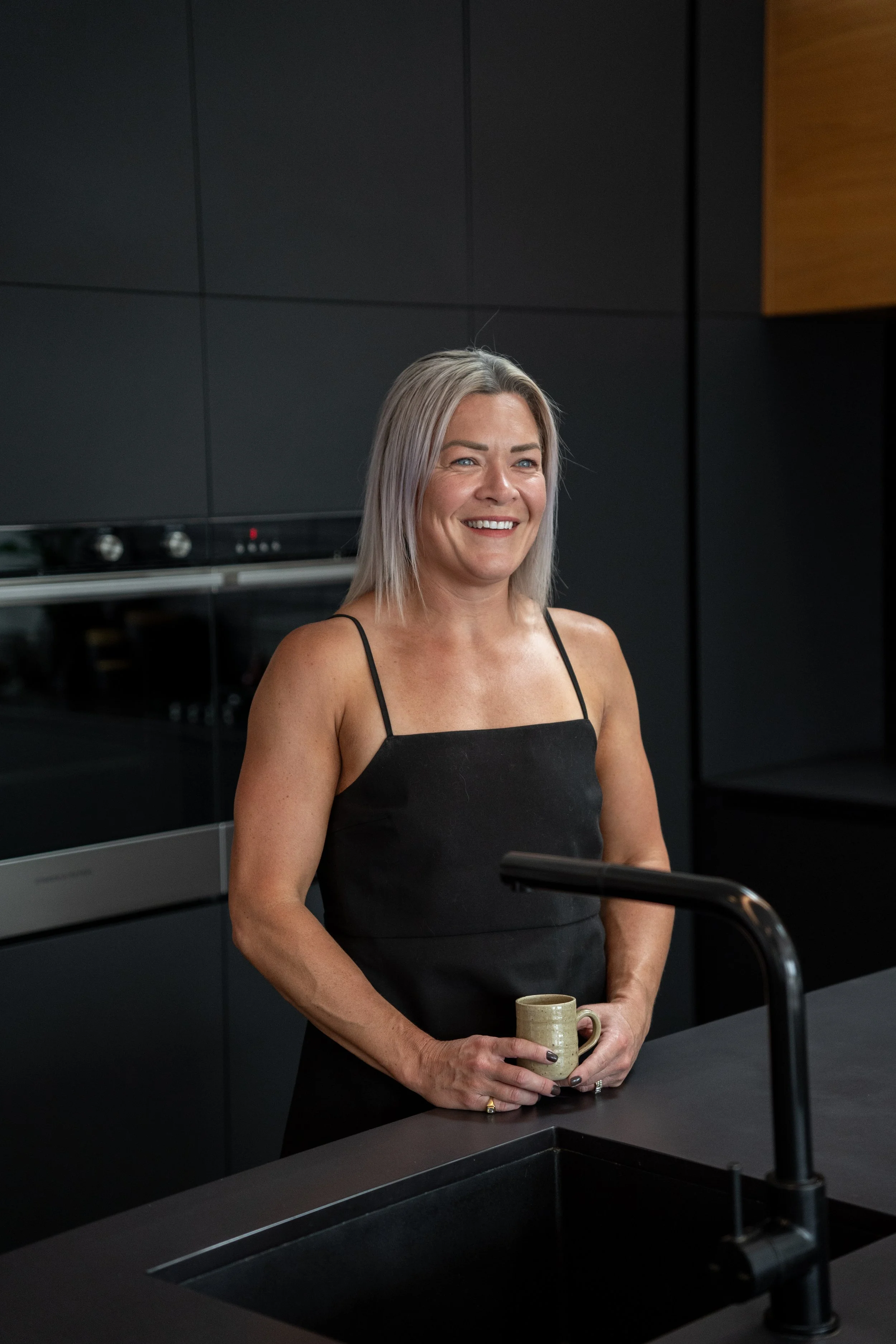 Person smiling in a modern kitchen holding a cup