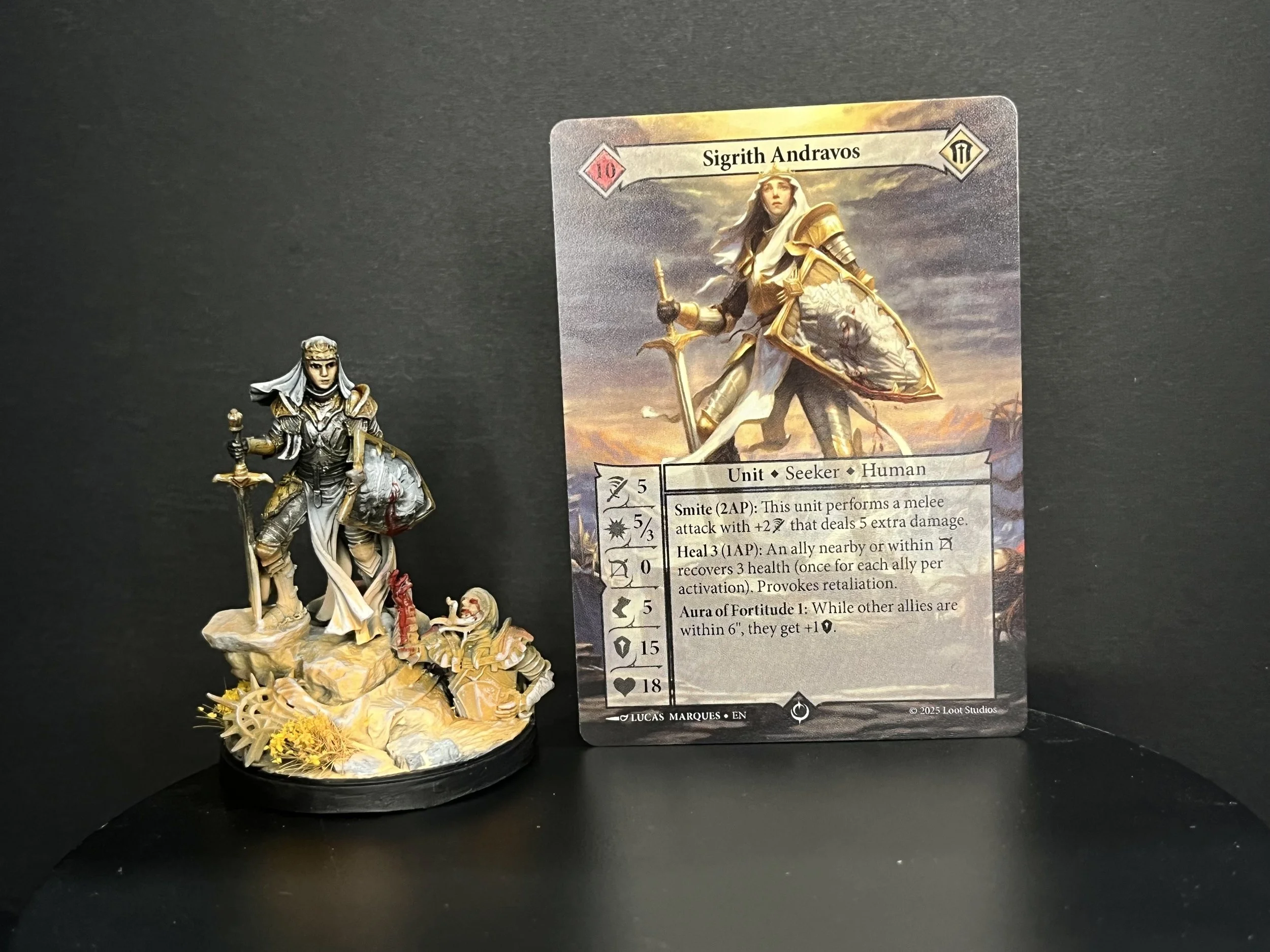 Miniature figure of a female knight holding a sword and a shield, standing on a detailed base with gears and yellow plants, next to a trading card depicting the same character named Sigrith Andravos in medieval armor.