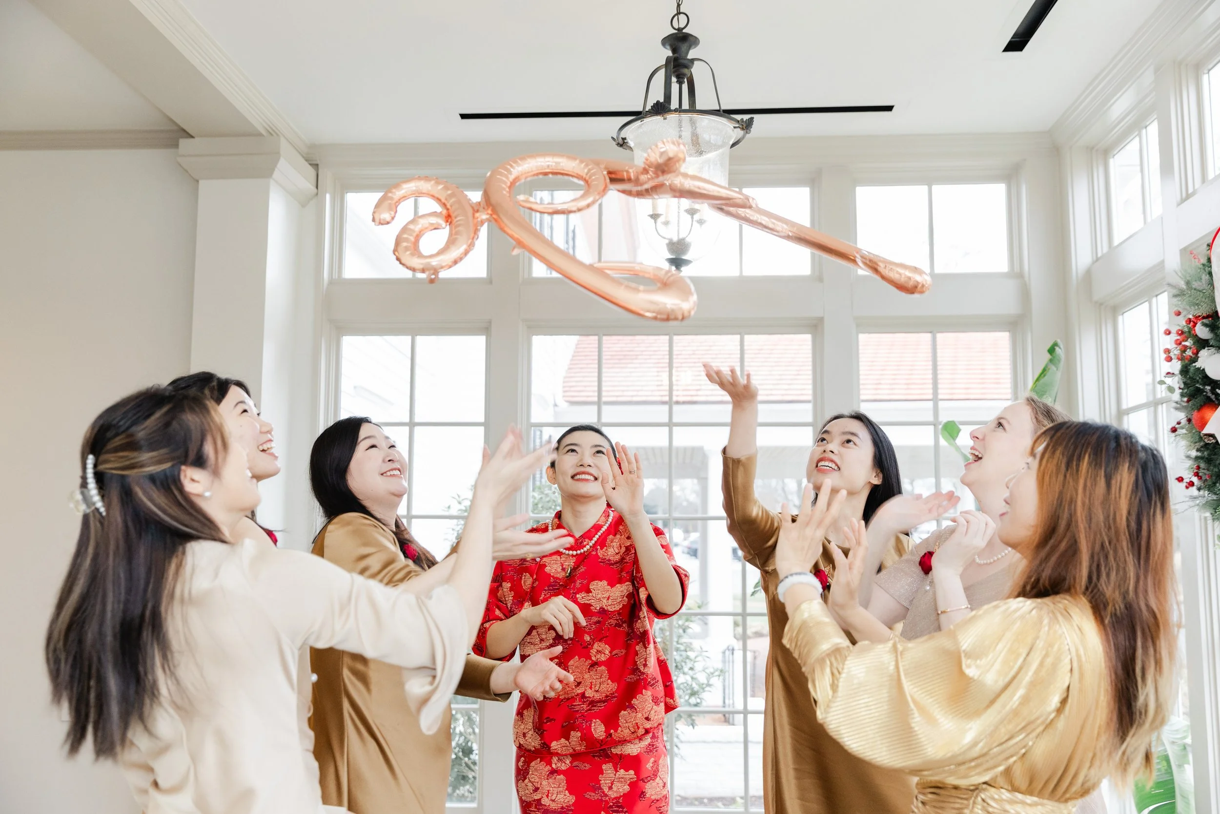 Group of women celebrating indoors with a pink balloon octopus floating above them.