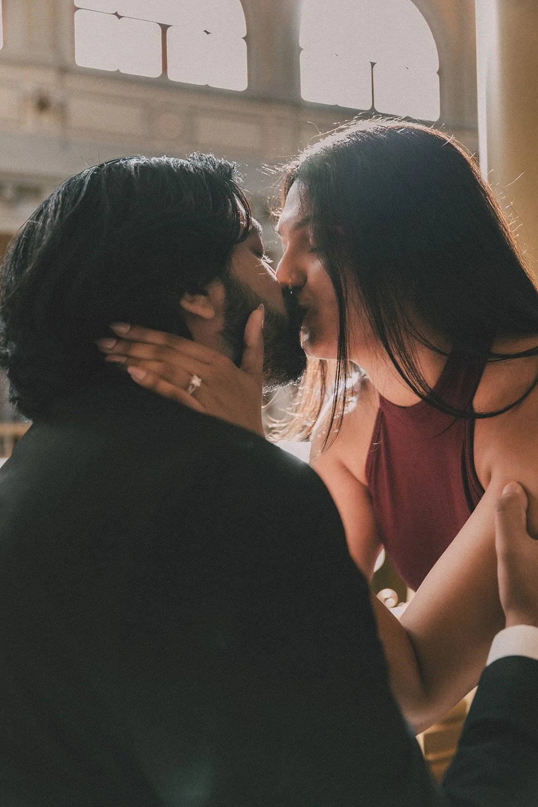 A couple sharing a kiss inside a warmly lit room.