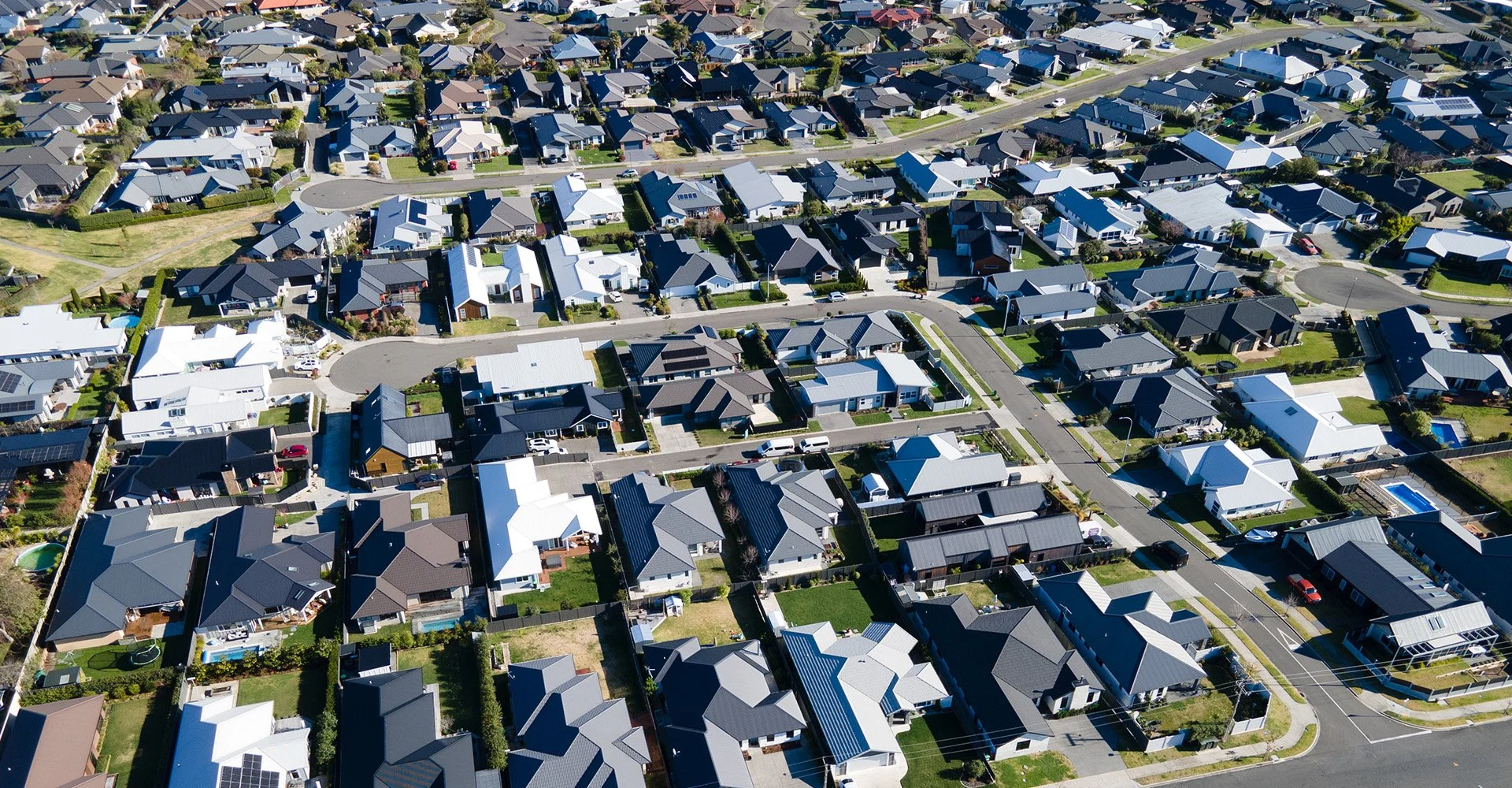 Civil Engineering - Strata Group Engineers NZ | Aerial view of a suburban neighborhood with rows of houses, streets, and green lawns.