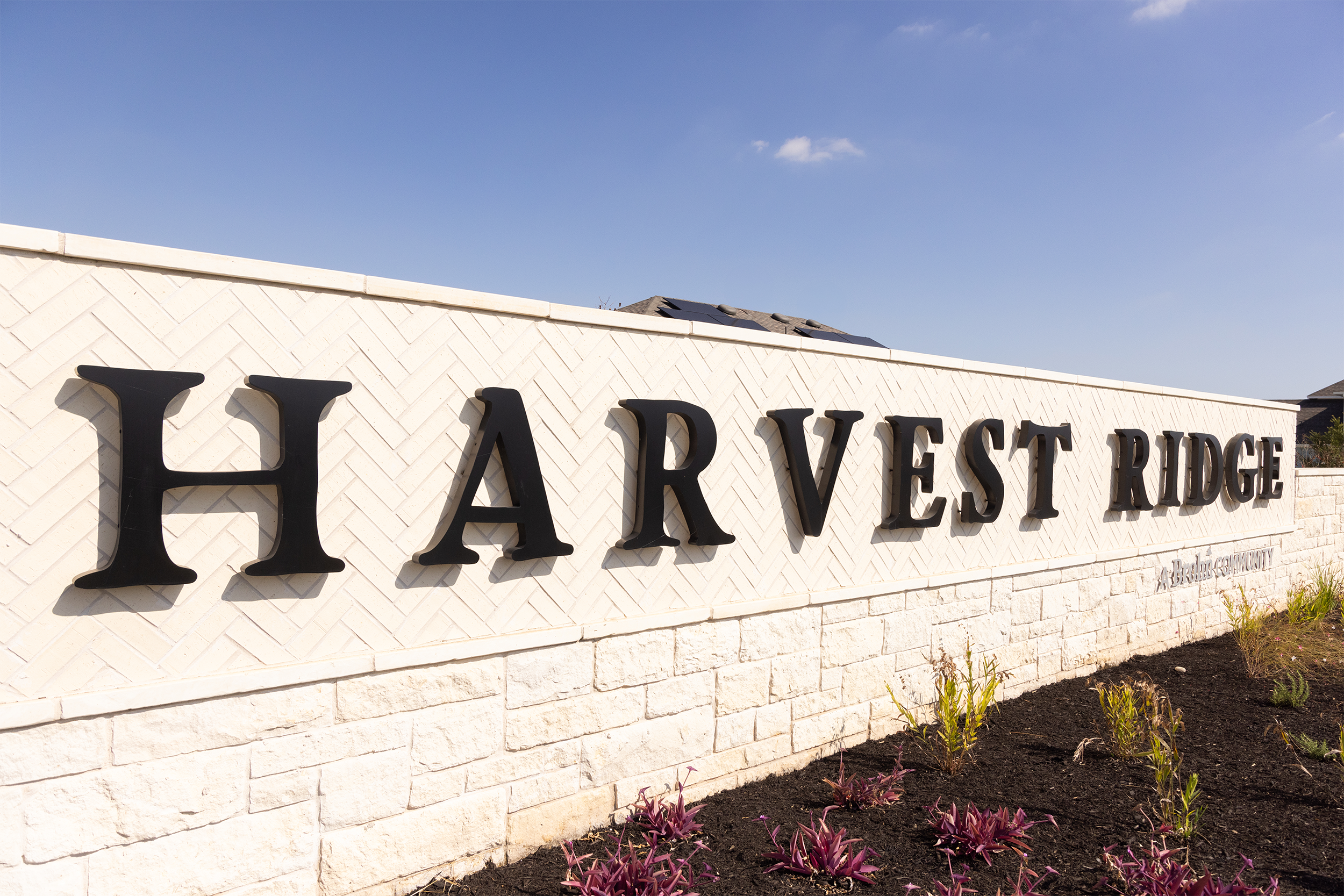 Entrance sign reading 'Harvest Ridge' on a stone wall with landscaping