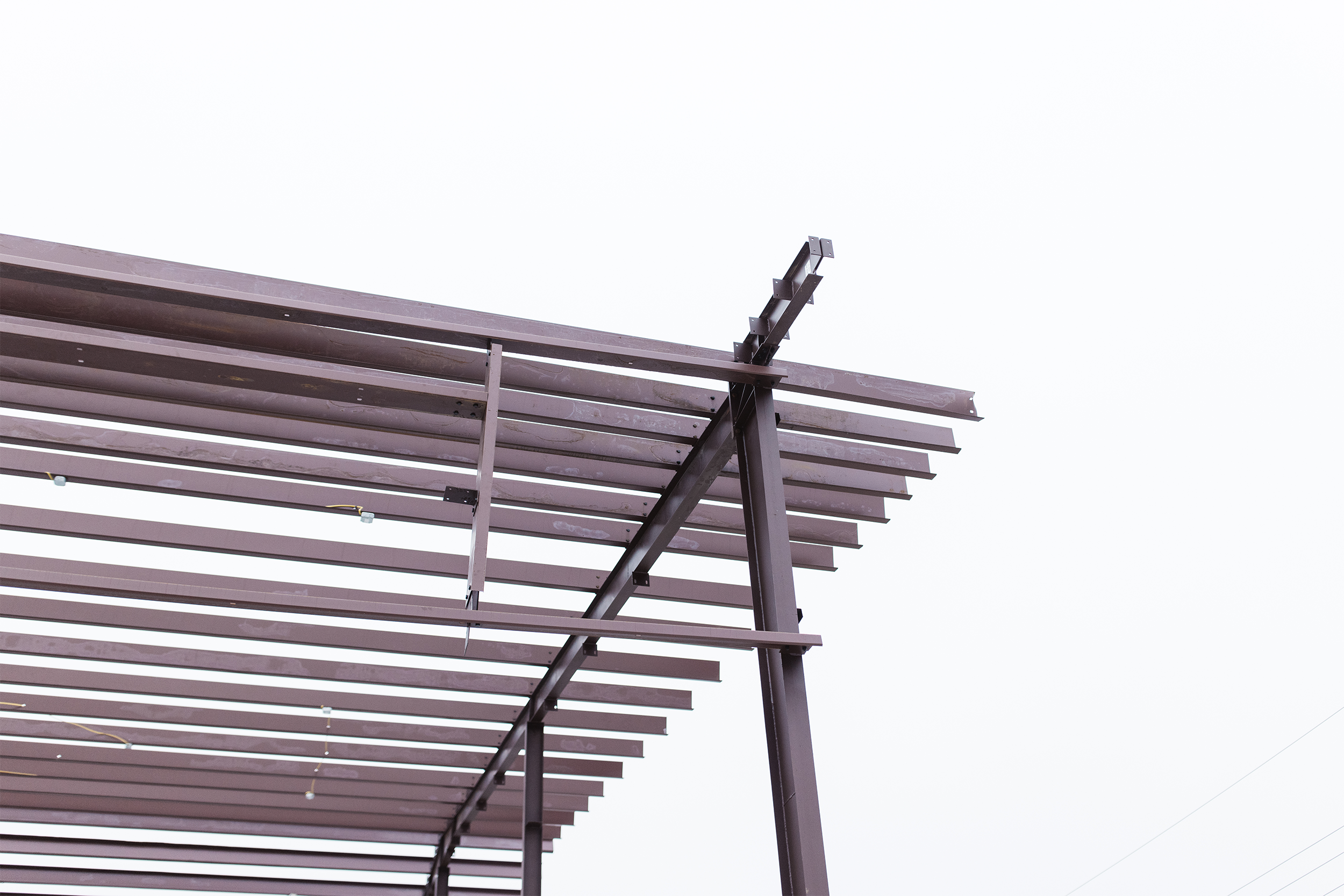 Partial view of a metal pergola structure against a gray sky.