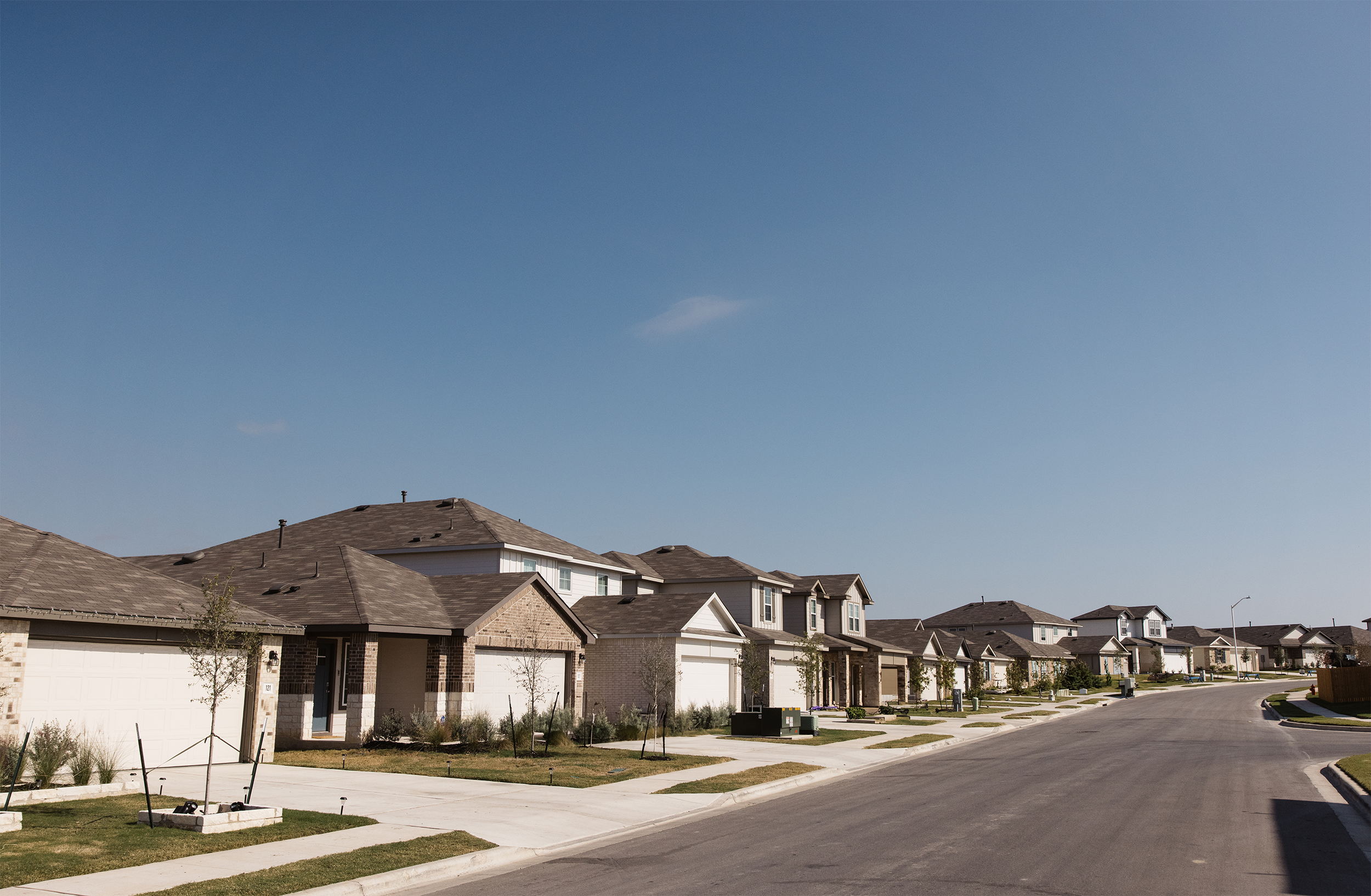 Suburban neighborhood with row of modern houses, clear blue sky