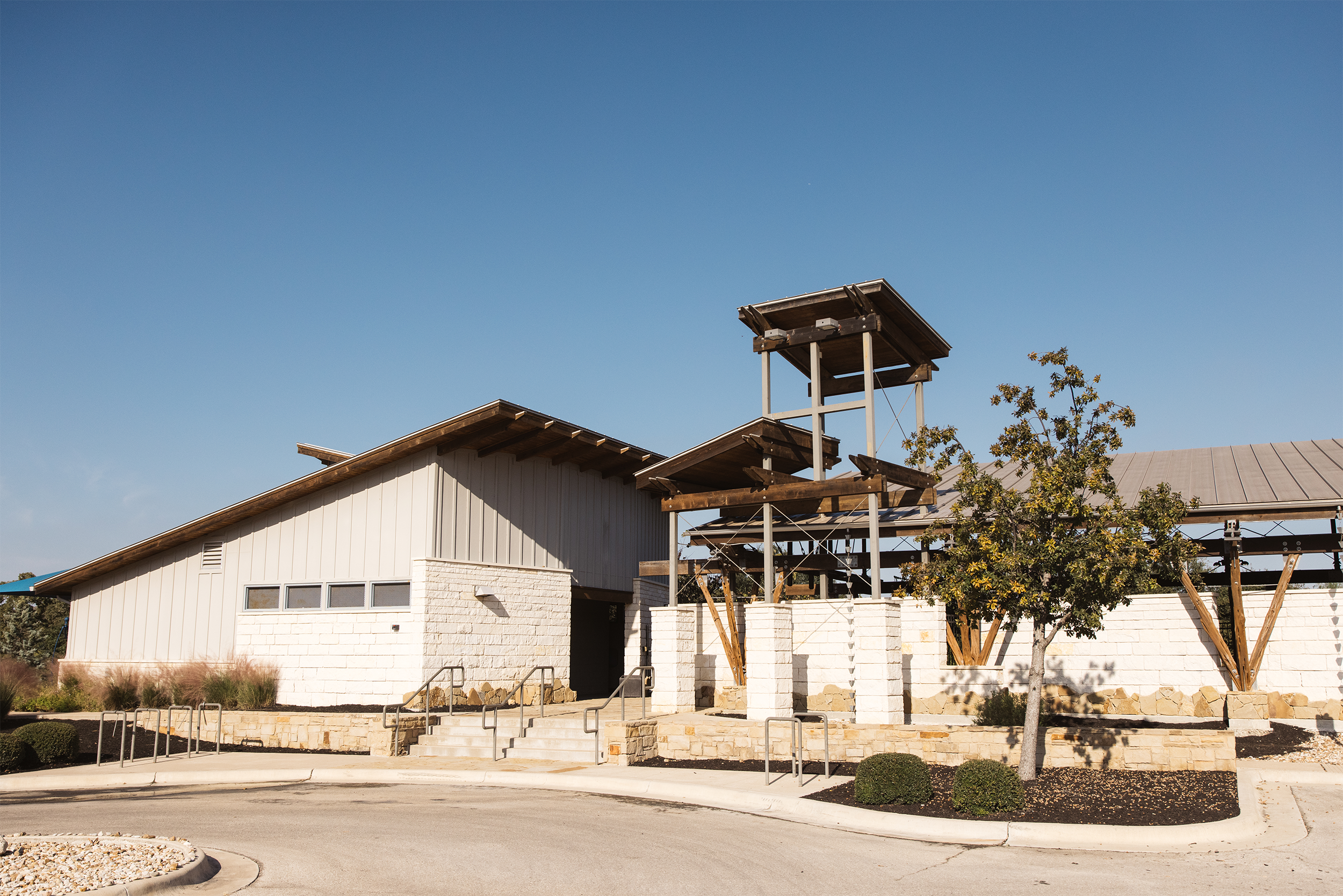 Modern building with wooden and stone elements under a clear blue sky