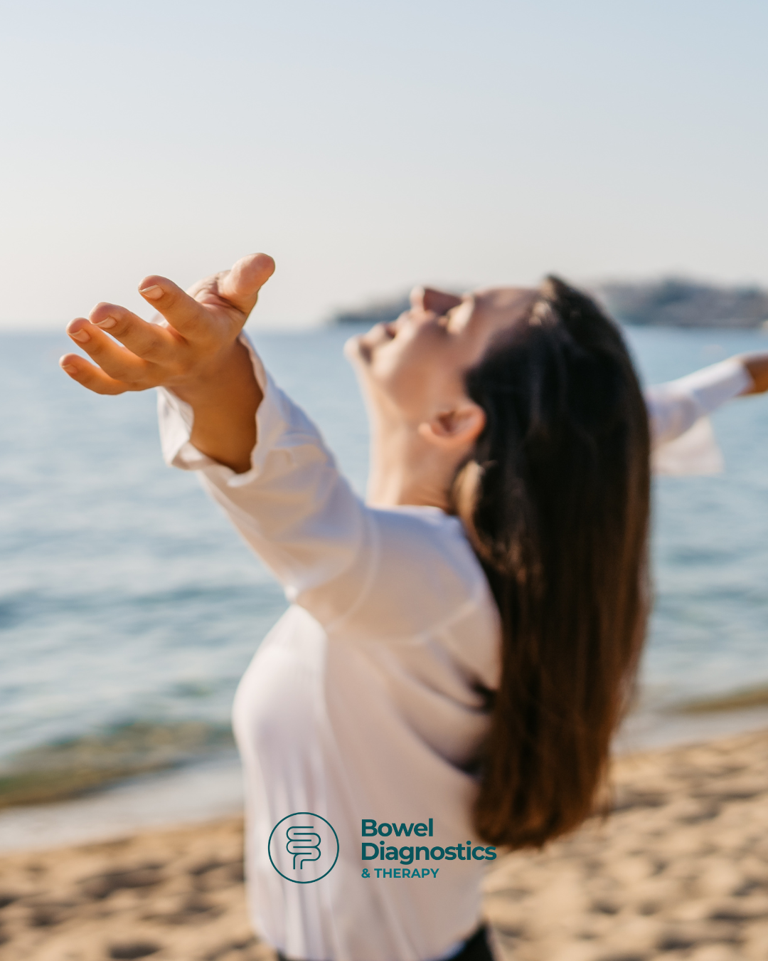 Woman beach facing sun arms towards sky smiling no bowel symptoms diarrhoea constipation pain