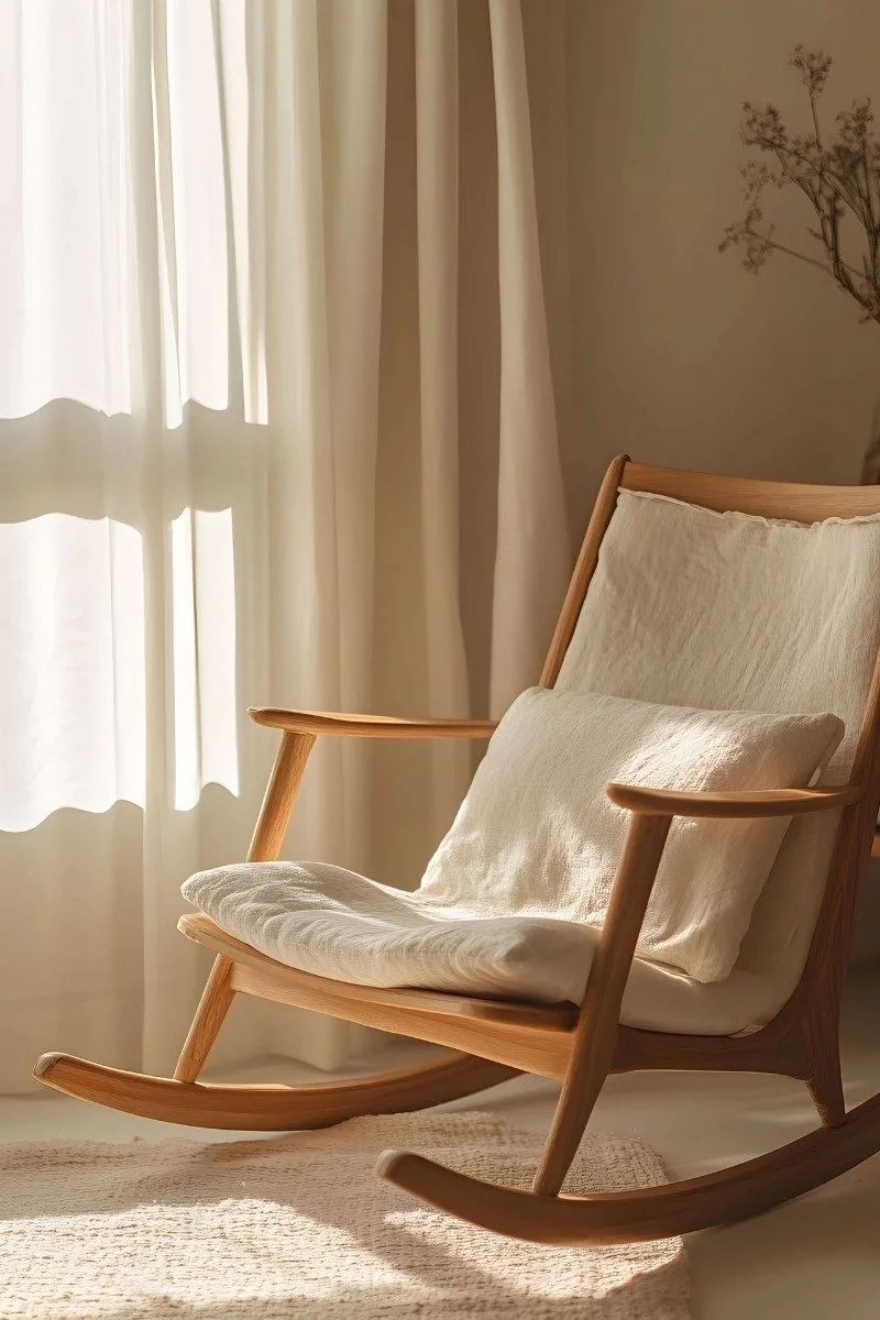 A cozy wooden rocking chair bathed in soft sunlight invites gentle movement, supporting nervous system regulation through the calming rhythm of rocking. A serene space for holistic women's mental health and polyvagal therapy in California.