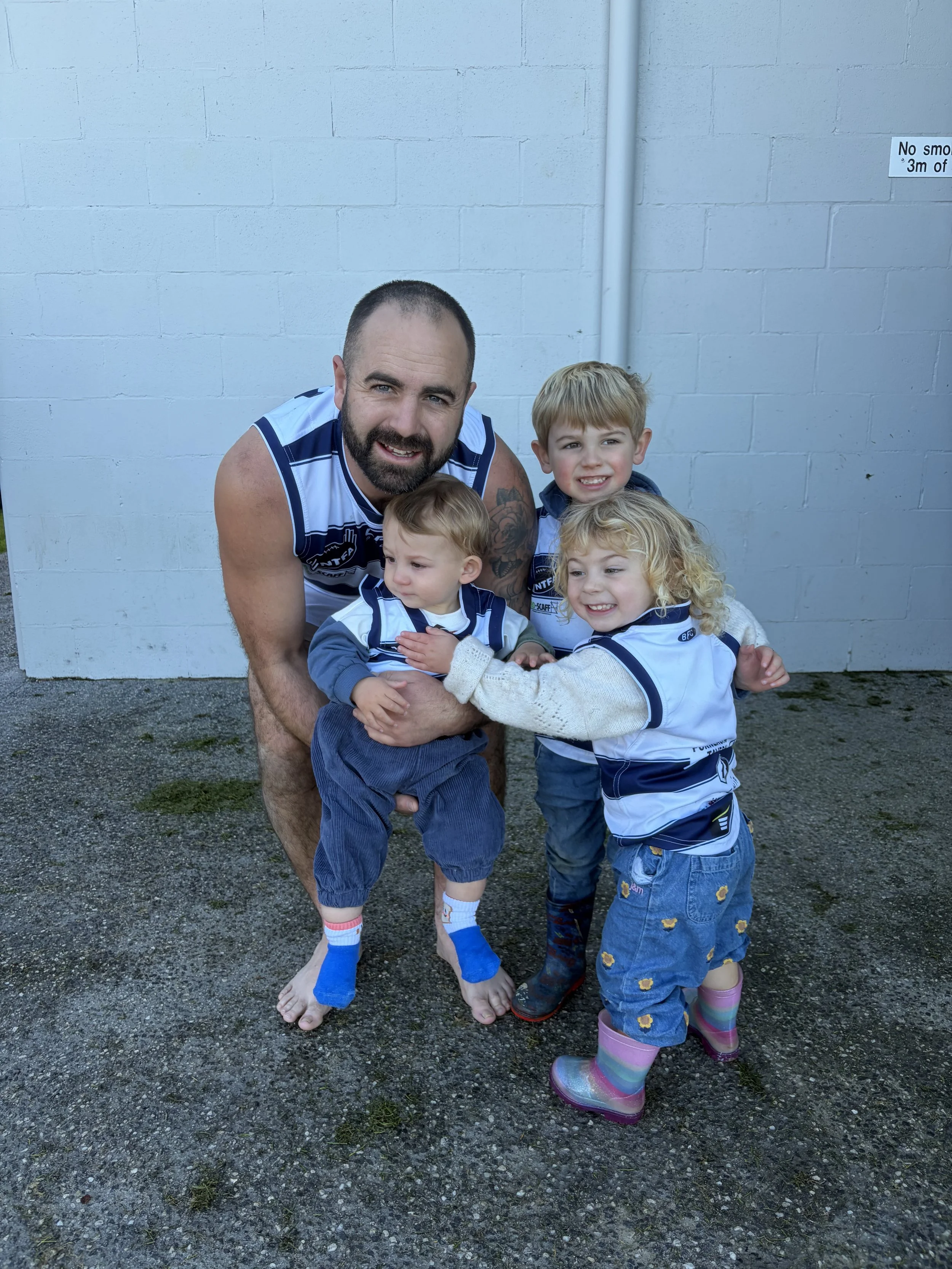 Man in Bridport Football Club uniform with three children
