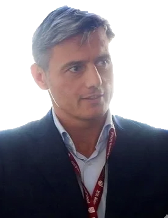 A man with gray hair wearing a dark suit and white shirt, with a red lanyard around his neck.
