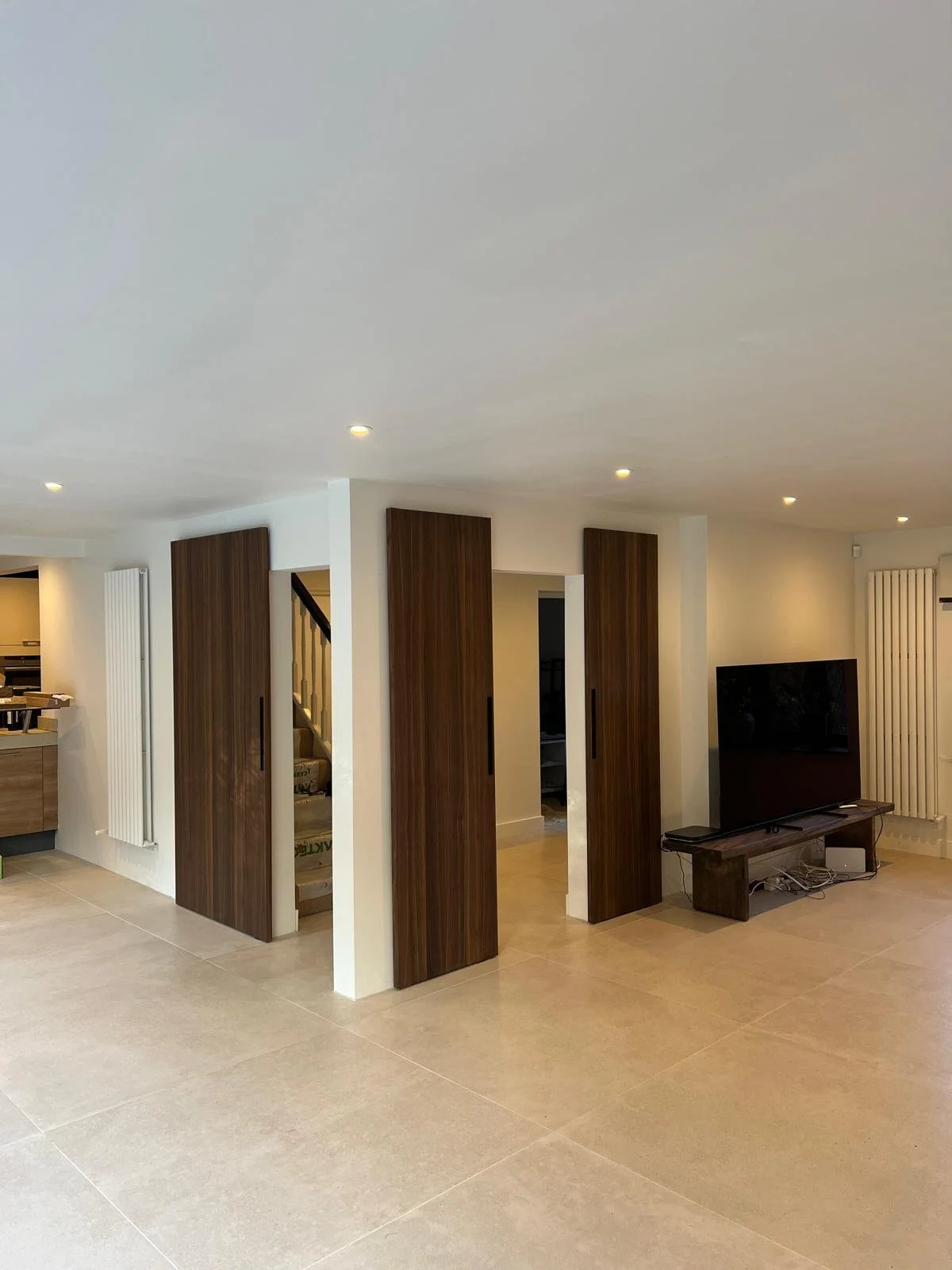 Downstairs reception room renovation with automatic dark wooden doors.
