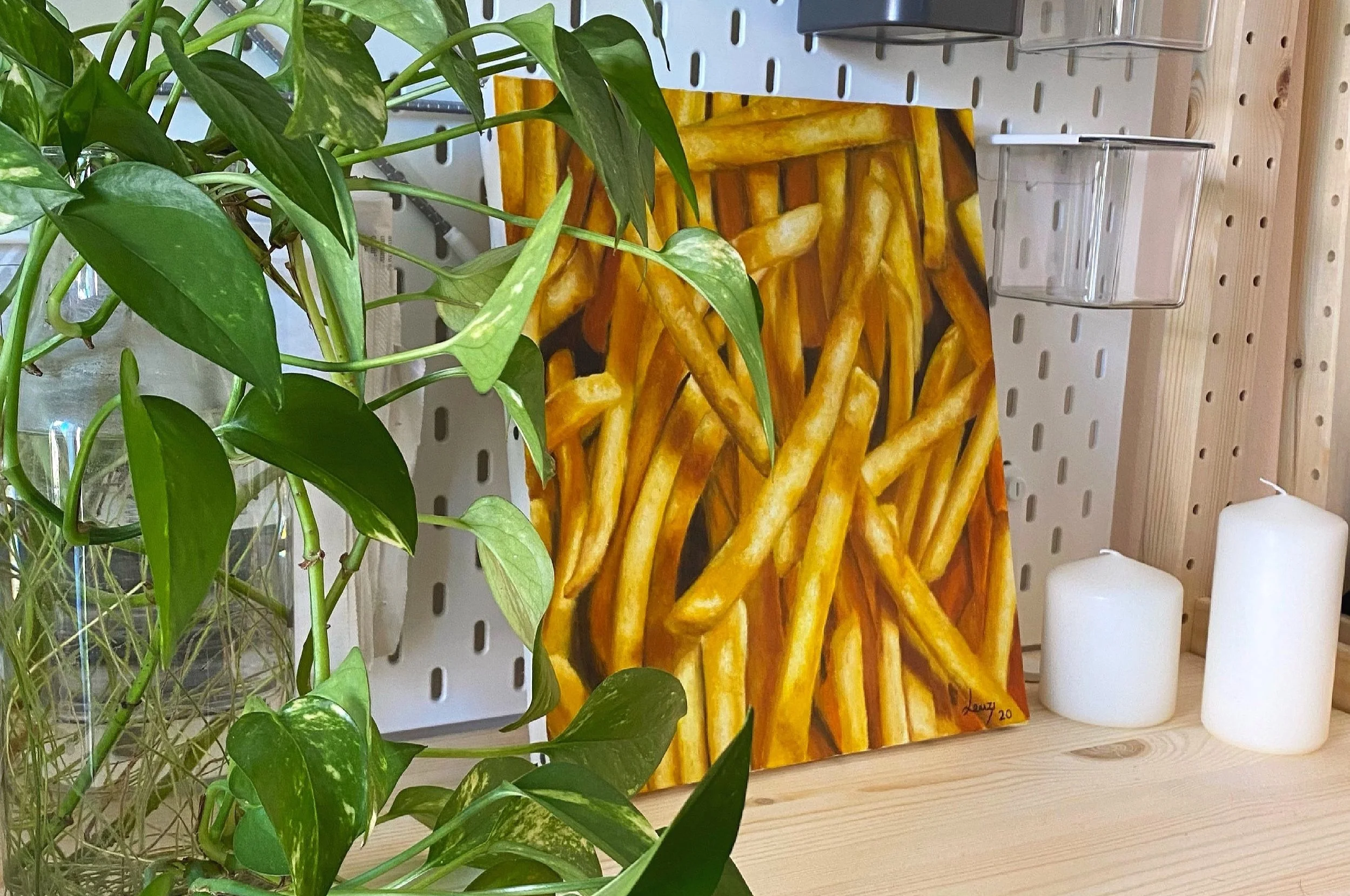 Interno di una stanza con una pianta verde e un quadro raffigurante patatine fritte.