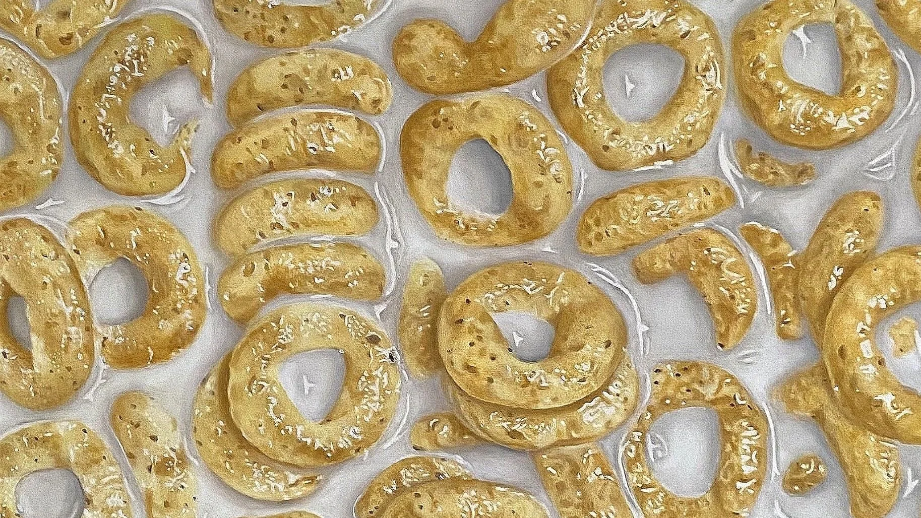 Anelli di pasta con semi di sesamo distribuiti su una superficie bianca.