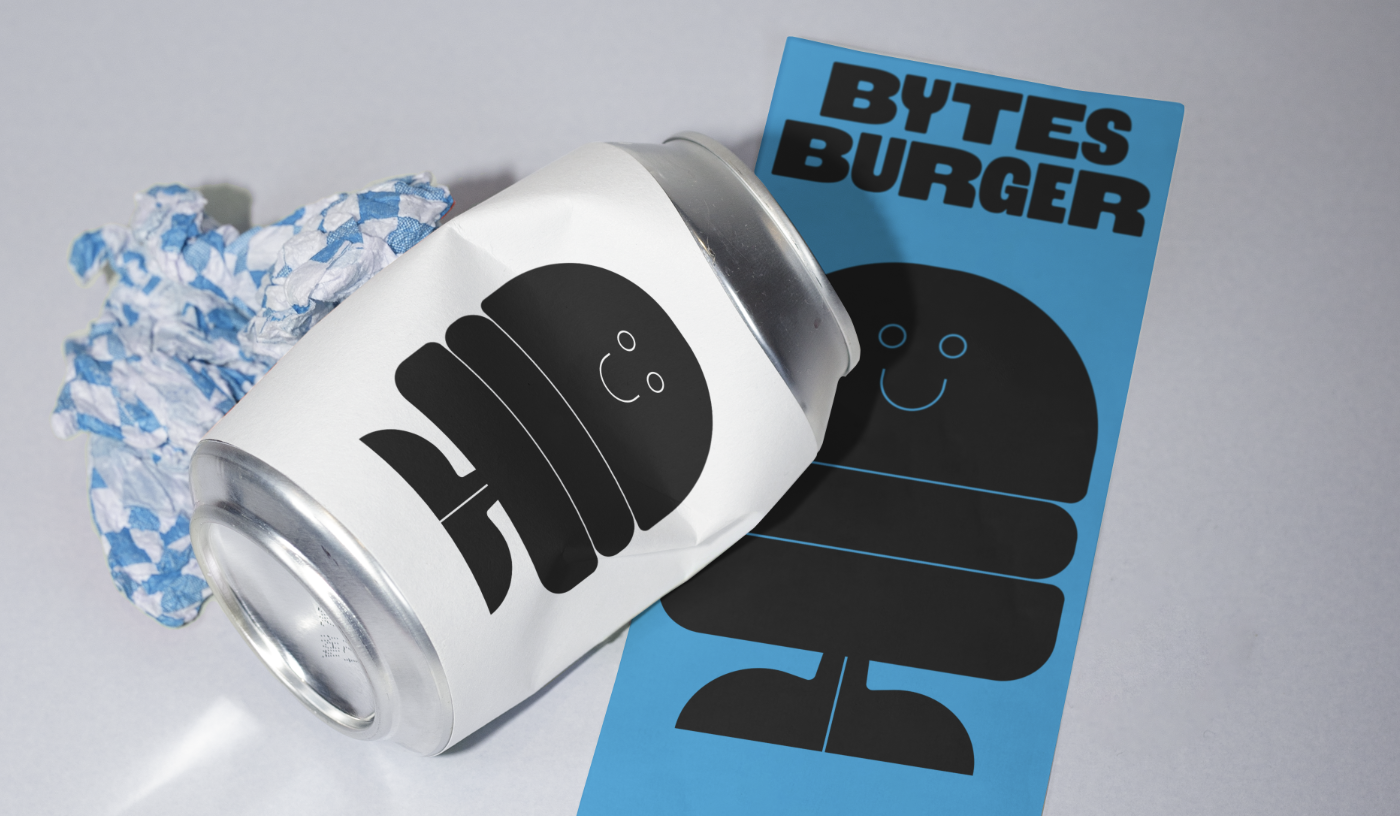 Lata de soda decorada con etiquetas de un payaso con sombrero, y una tarjeta azul con dibujo de payaso y texto 'Bytes Burger'.
