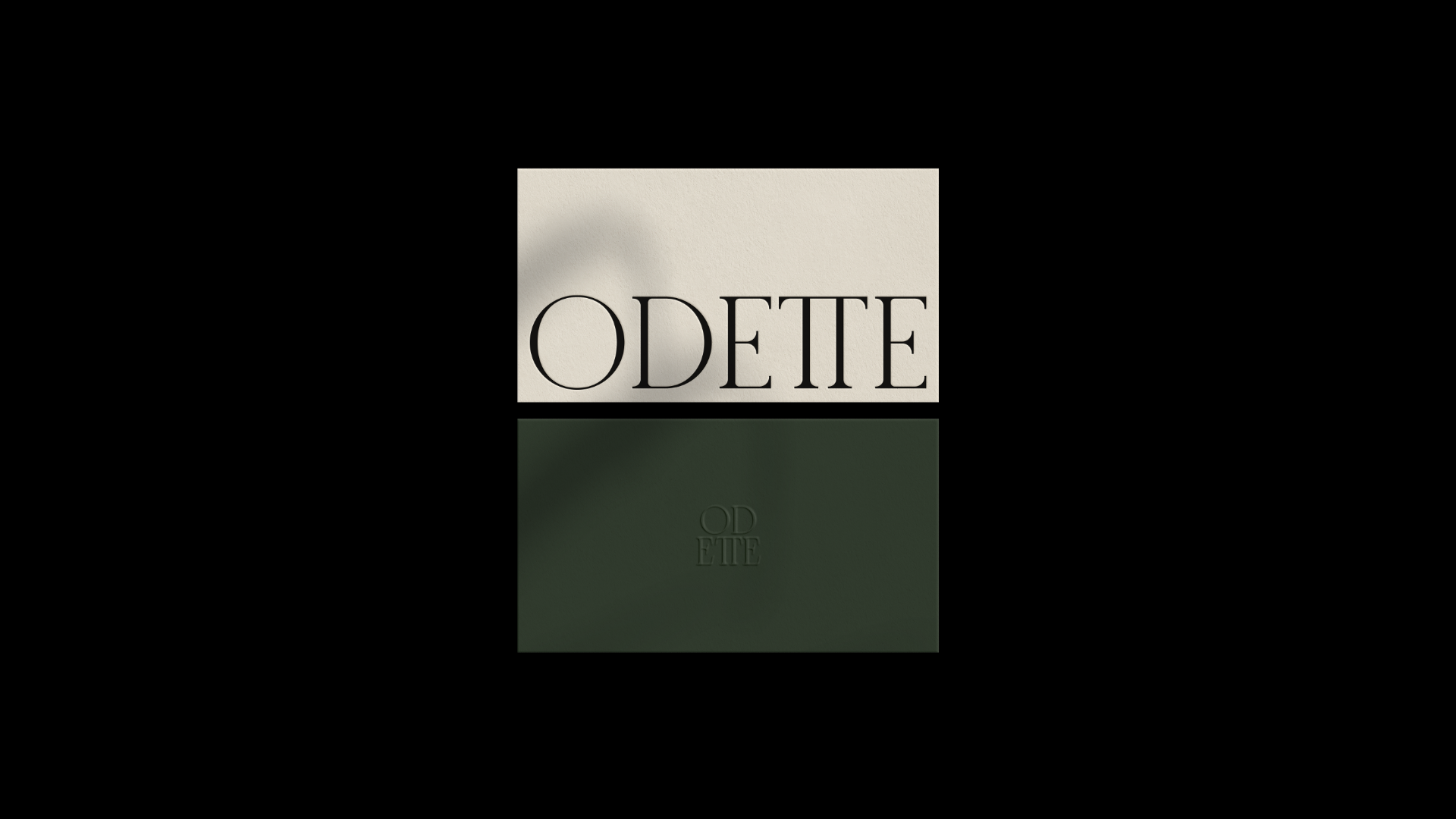 Caja de perfume con la palabra 'ODETE' en letras grandes en la parte frontal y reflejada en la superficie.