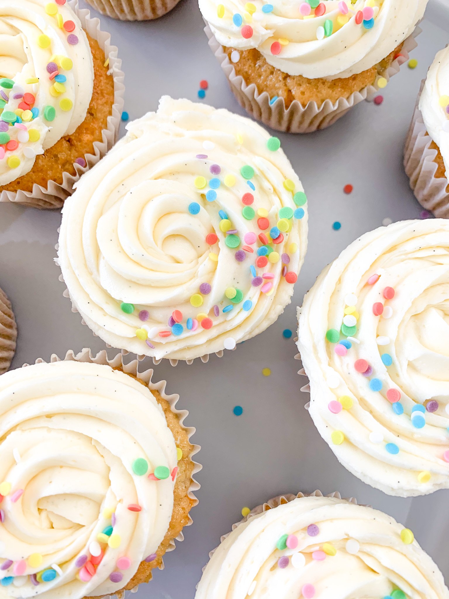 Cupcakes with white frosting and colorful sprinkles.