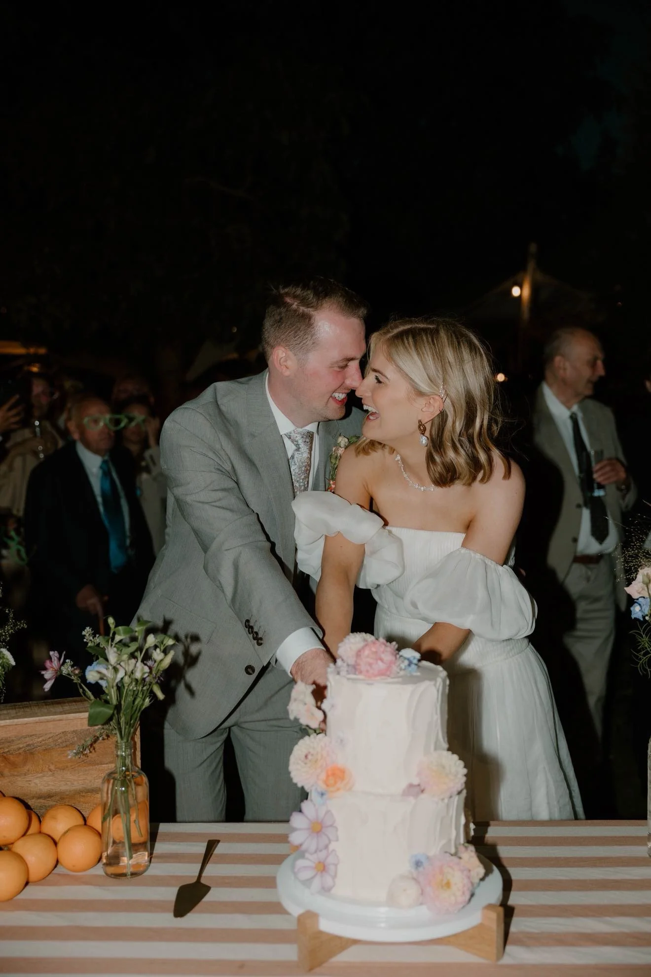 Happy couple cutting into their whimsical two-tier flower cake