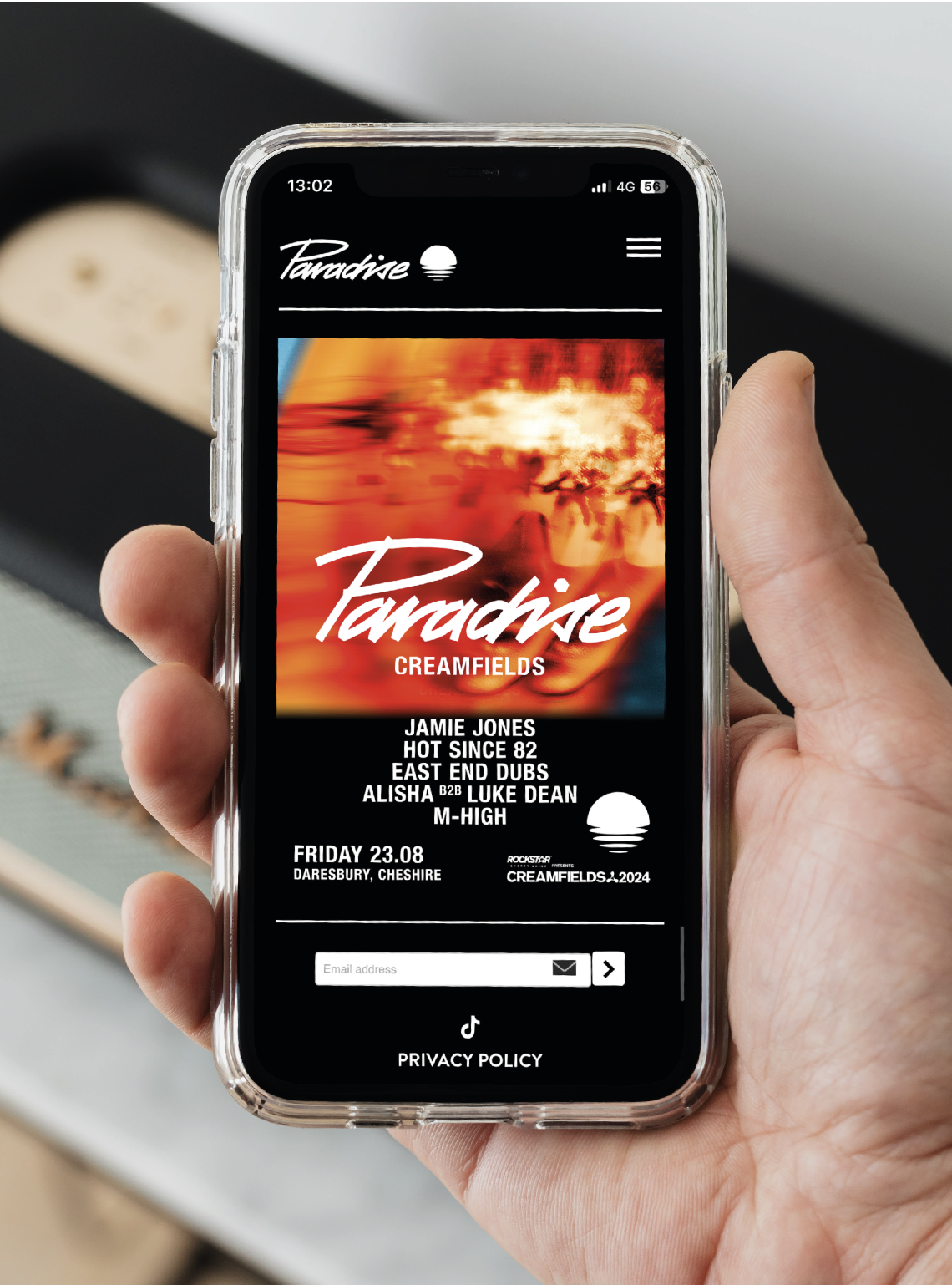 Website landing page for Jamie Jones presents Paradise Creamfields displayed on a smartphone, featuring a bright orange graphic design and complete DJ lineup for the music event.