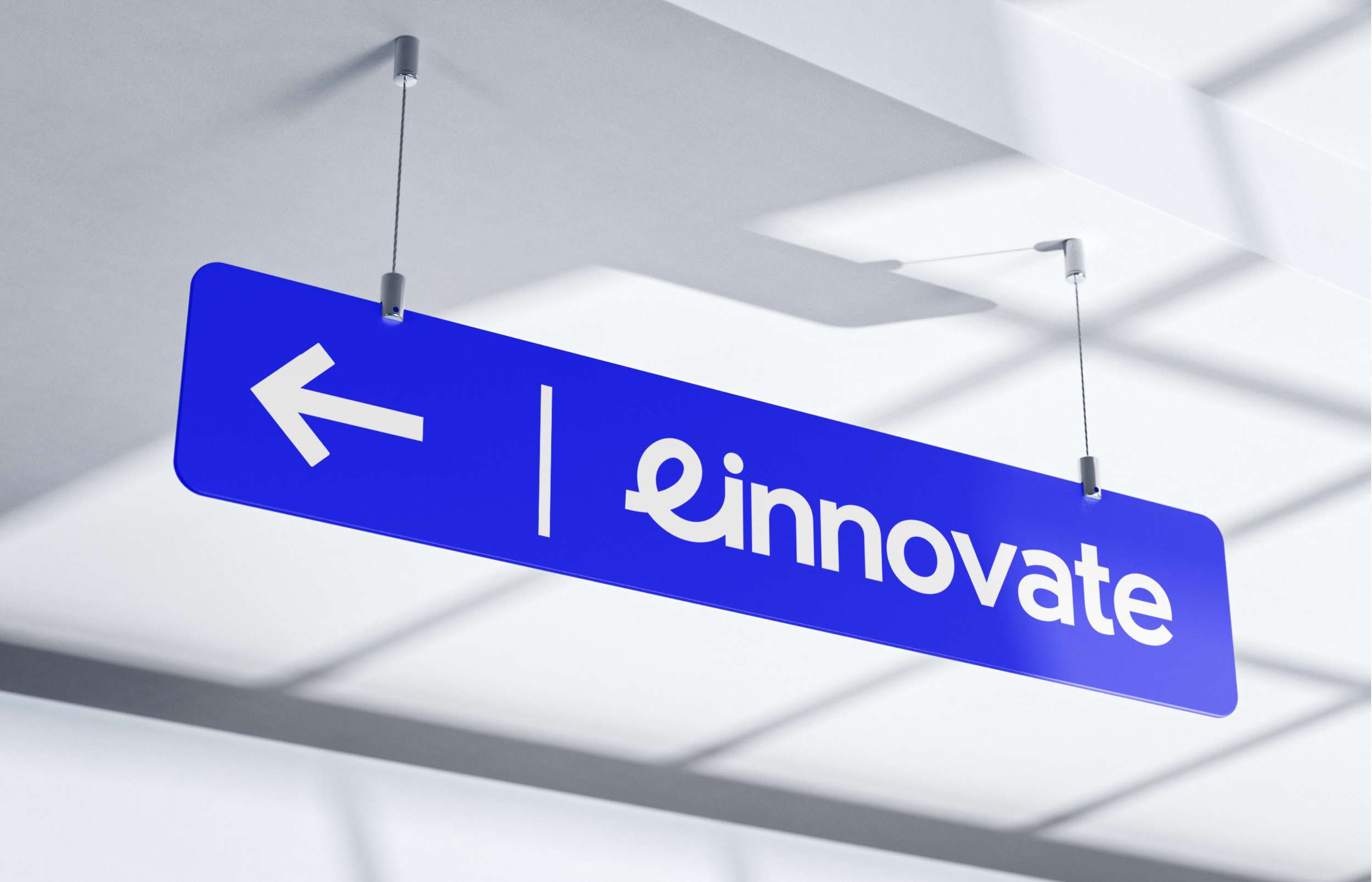 A bright blue ceiling-mounted sign with the word ‘einnovate’ and an arrow pointing to the left.