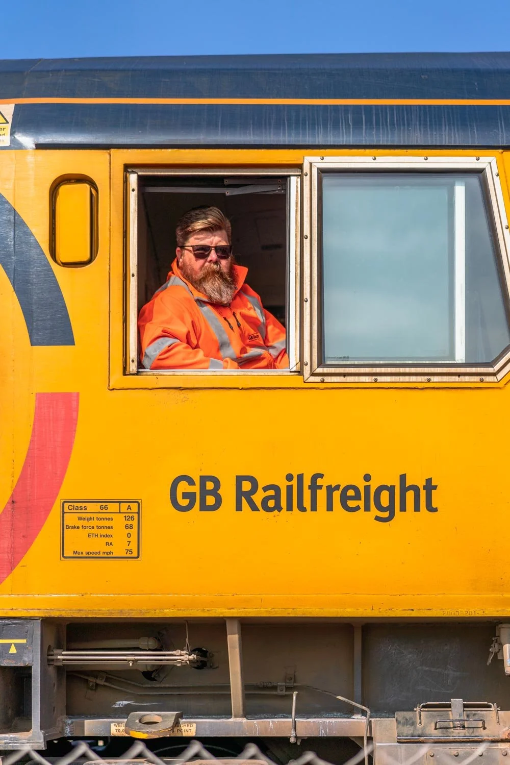 Close-up of a GB Railfreight driver sitting in the locomotive cab, smiling out of the window.