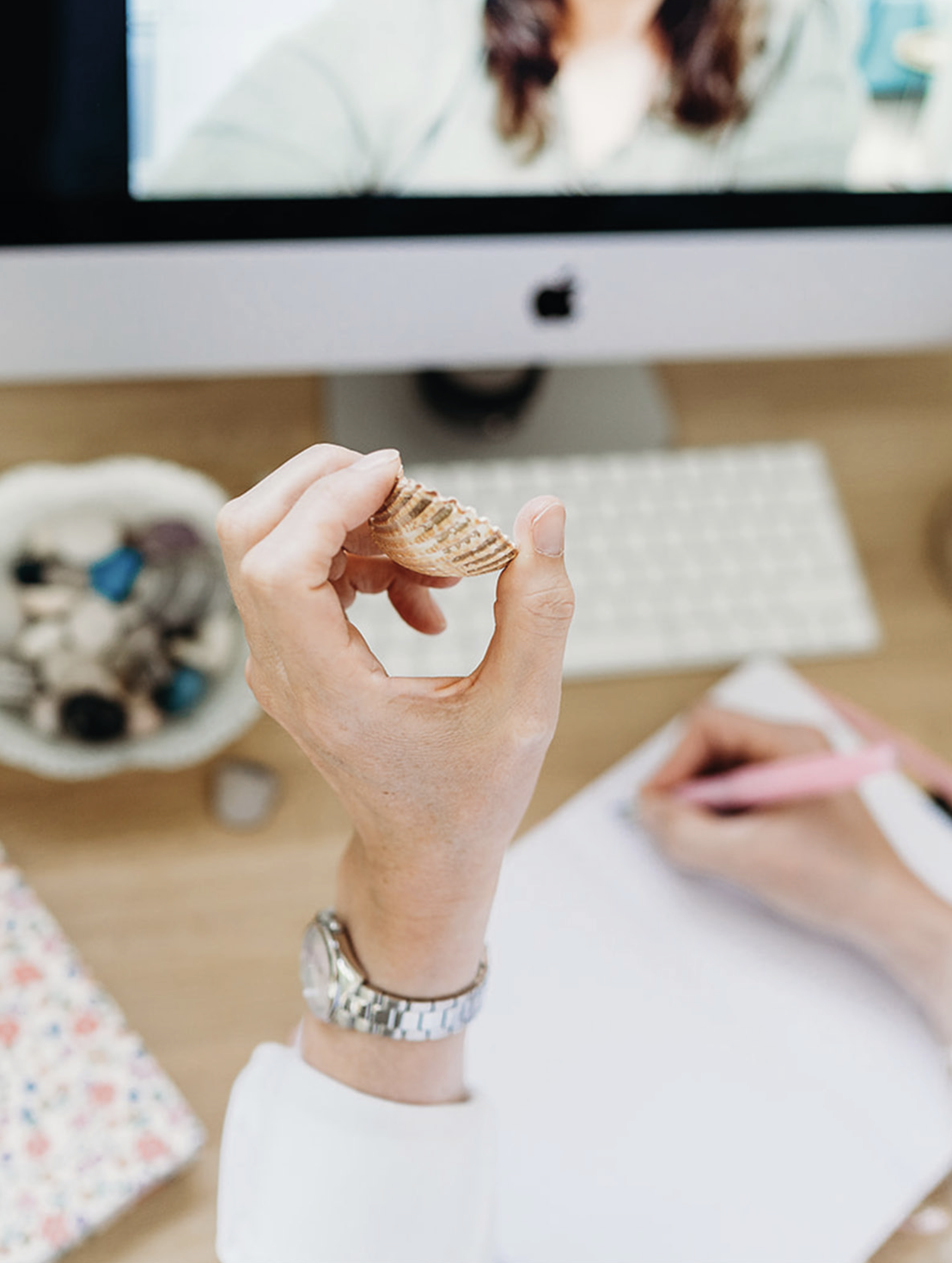 Person holding a seashell while sitting at a desk, adding a natural and emotional touch to Kora’s brand identity.